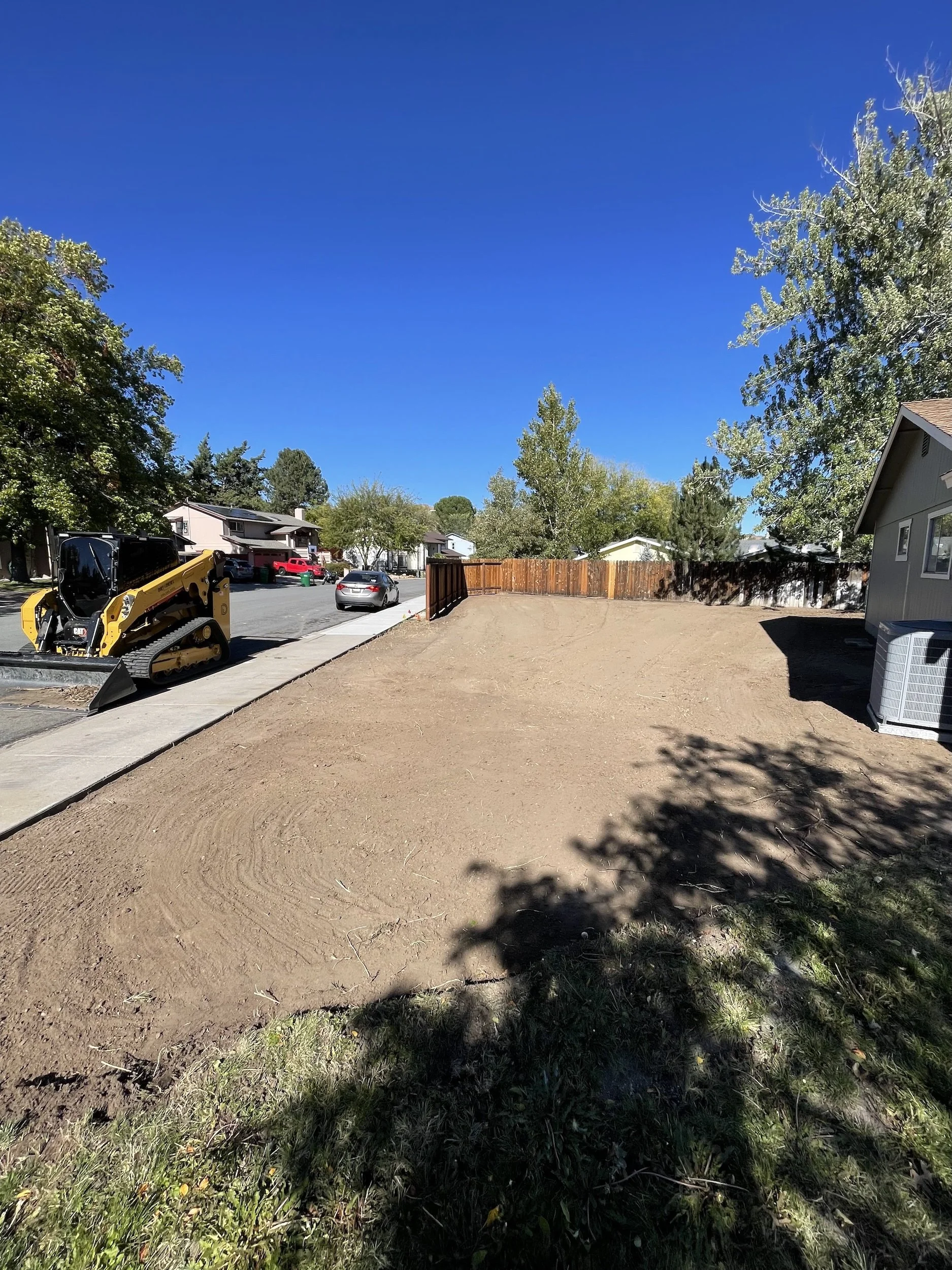 Track loader grading a front yard in a residential neighborhood