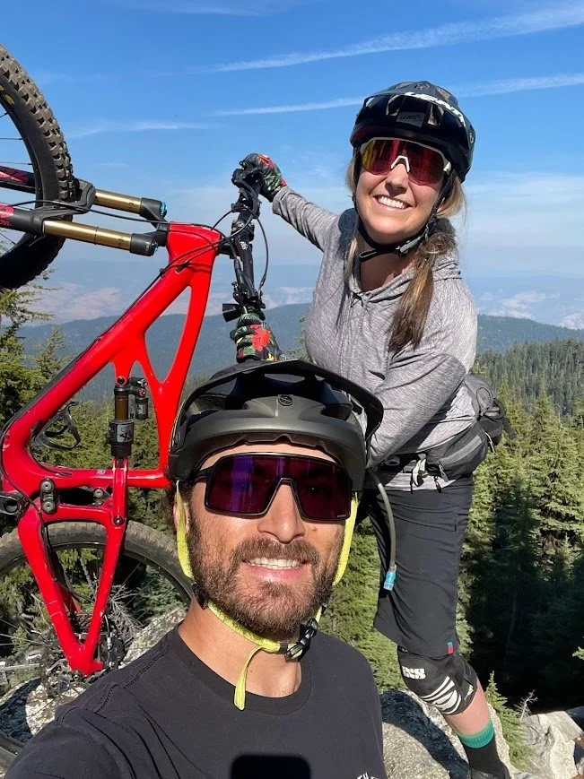Moriah holding up a mountain bike with Cooper in the front on a Northern Nevada ridge