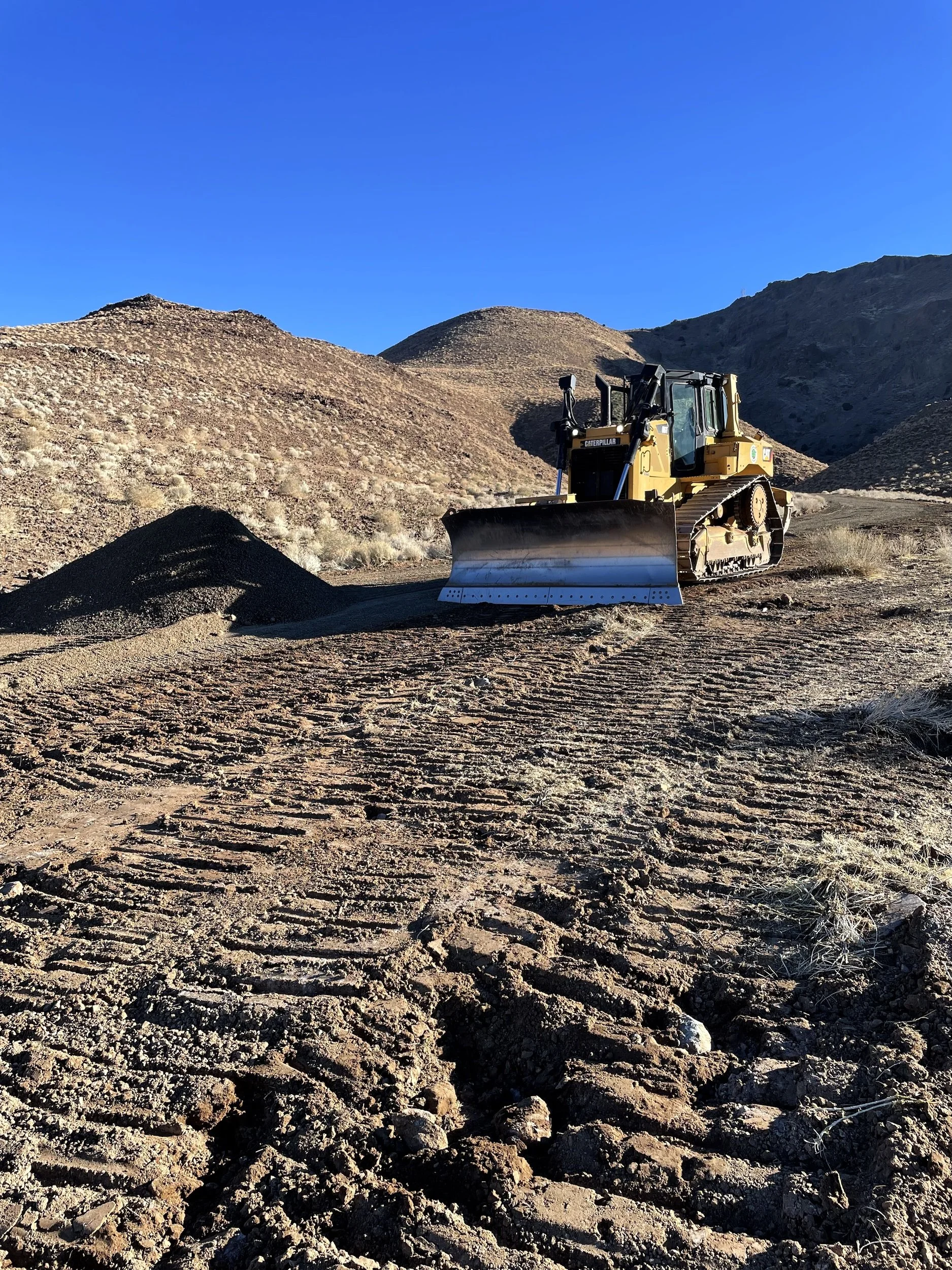 Dozer grading a dirt road cut into a hillside in Northern Nevada
