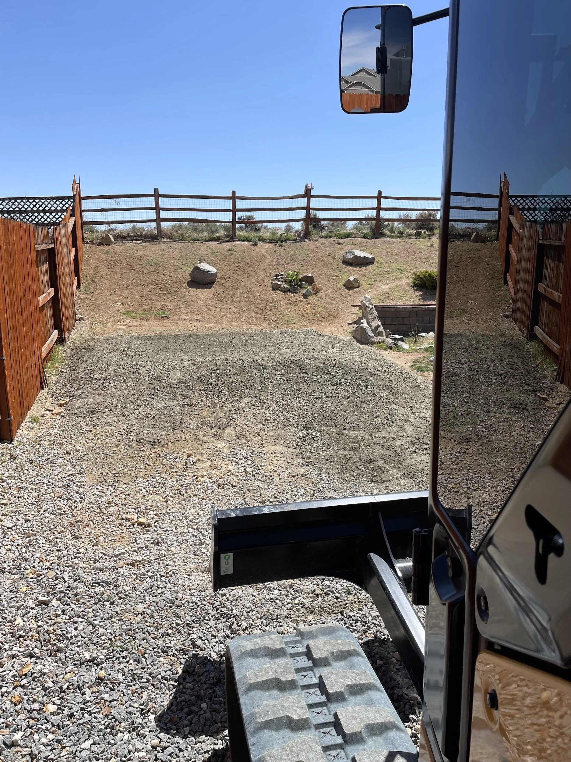 Graded gravel driveway leading up to a split-rail fence