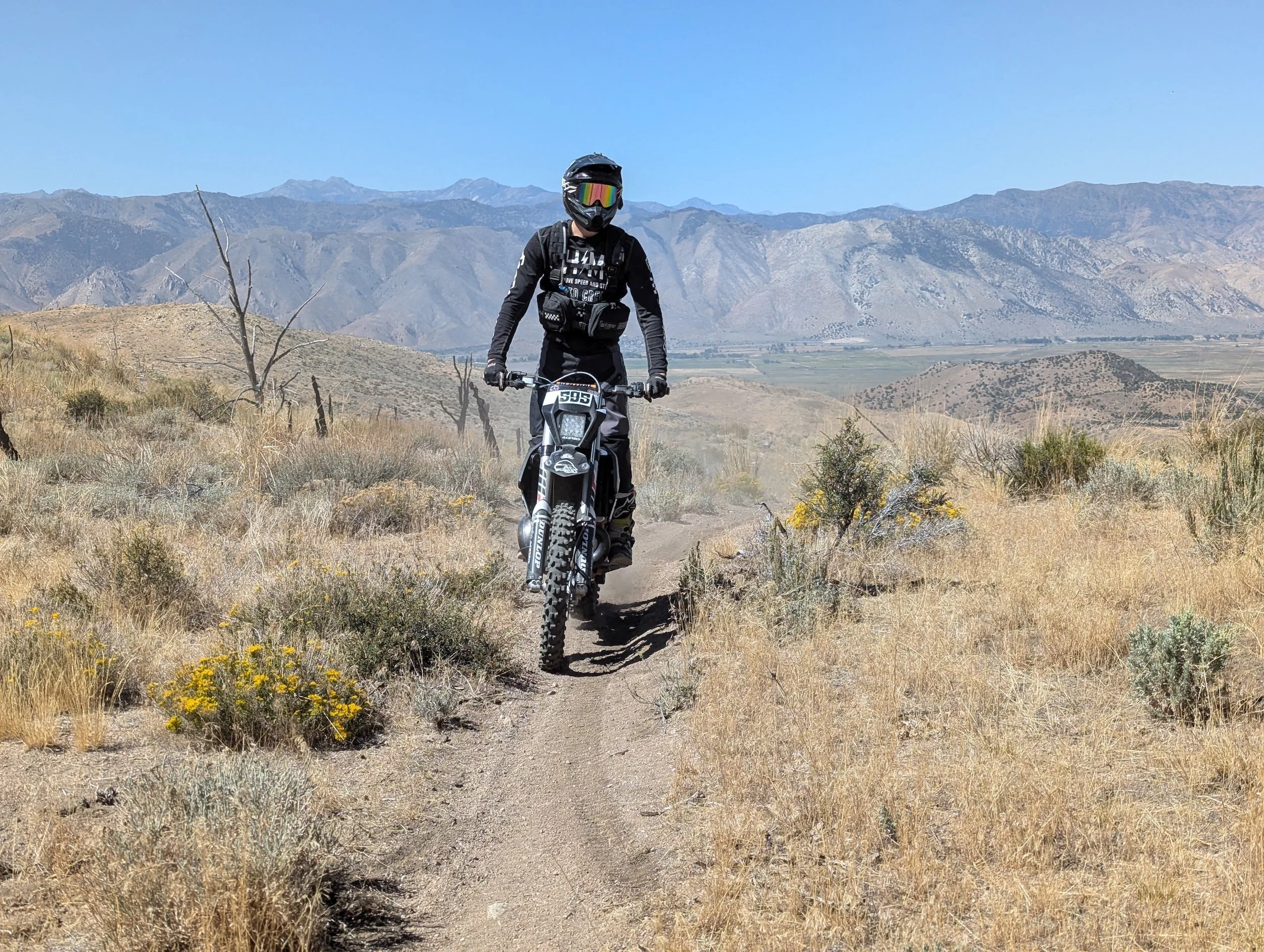 Dirt biker riding a singletrack trail on a sagebrush hillside in Northern Nevada