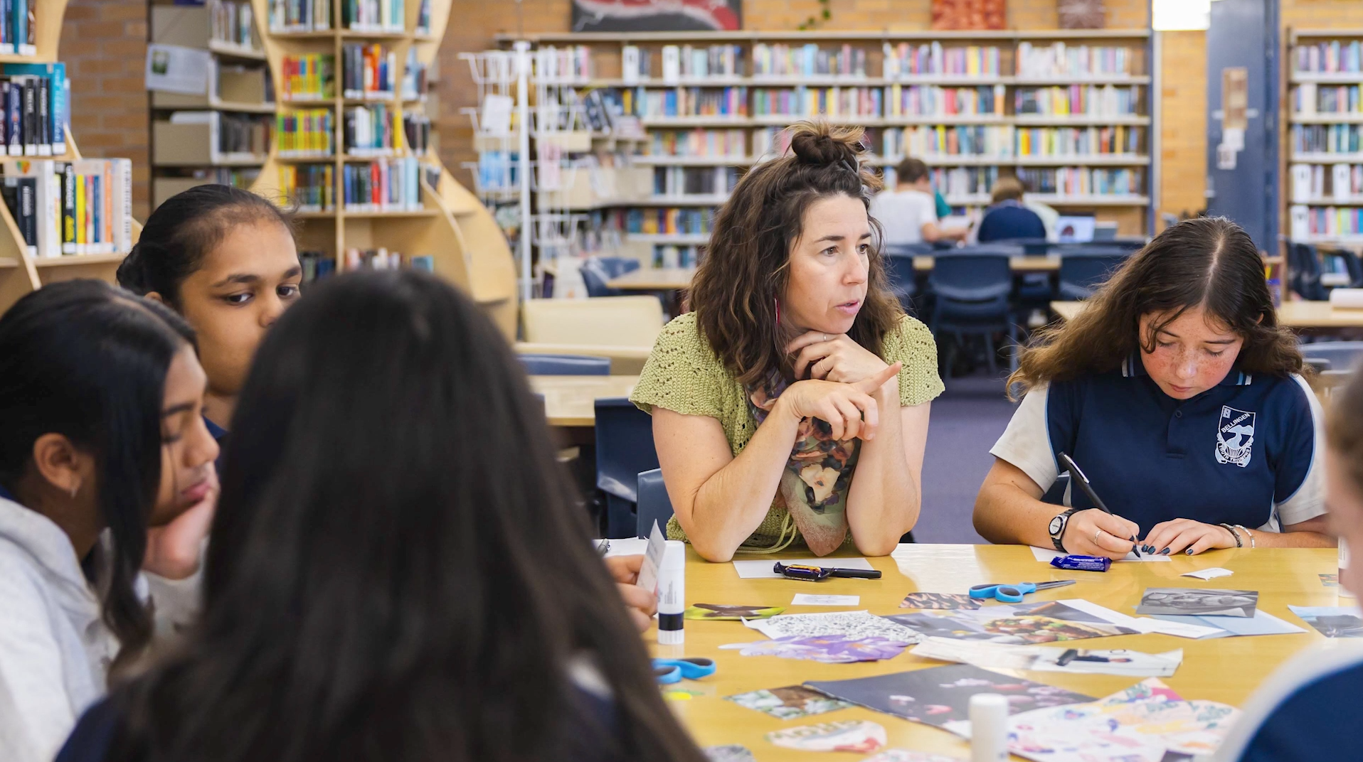 Miranda from Happymess Studio speaking with a group of high school students who are creating collage postcards