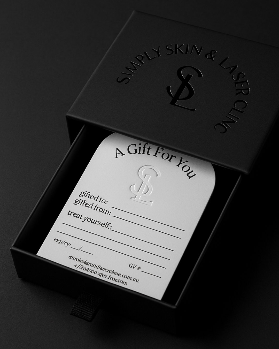 A black gift box with embossed text and logo on the lid, containing a white gift tag with space for customizing recipient, sender, and a message.