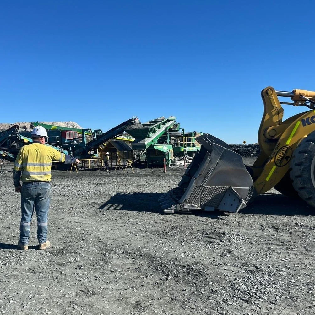 View of a construction or mining site with a large pile of white material, heavy machinery, and dark storm clouds in the sky.