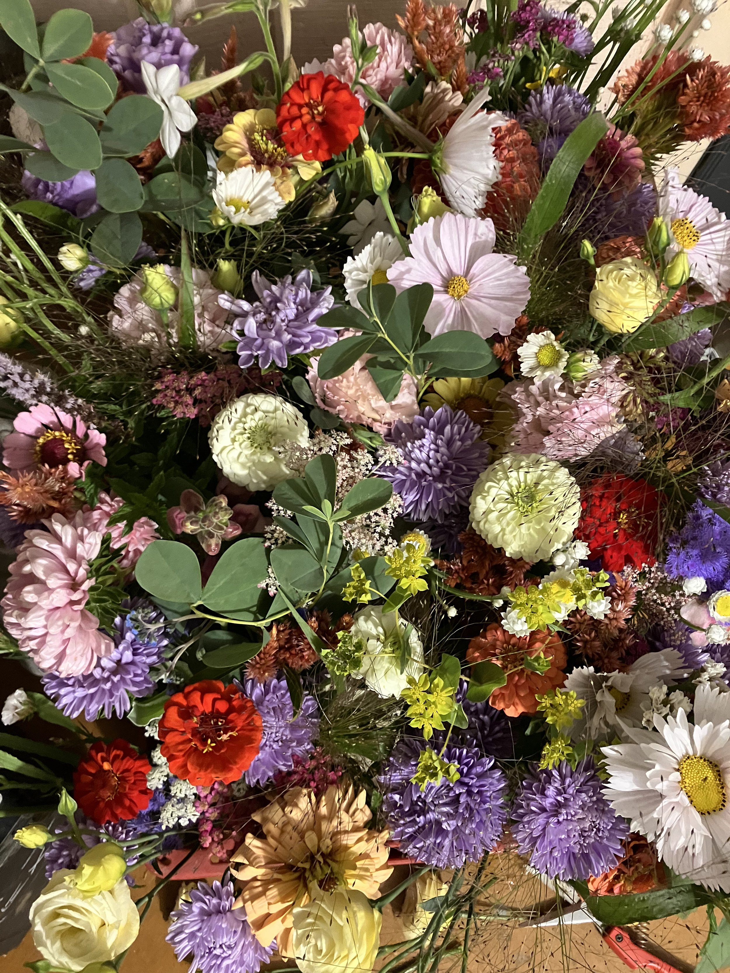 A cluster of bud vases has zinnias, cosmos, lisianthus, asters, and lots of textural elements. 