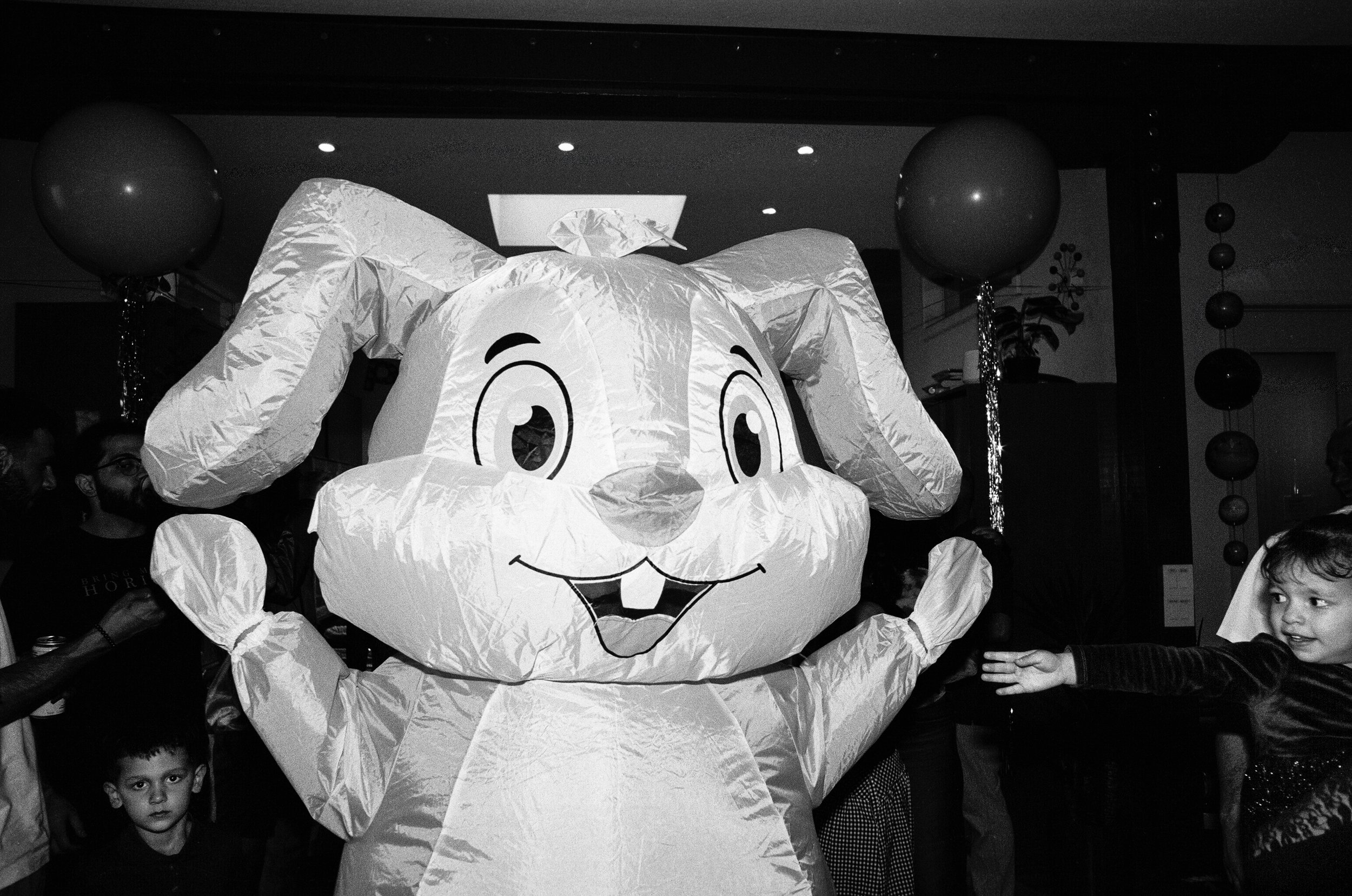 Children at a party interacting with a large cartoon bunny character costume.