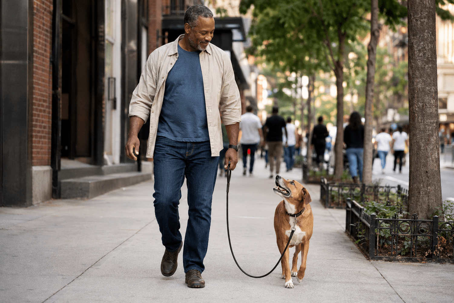 A dog walking politely on a loose, slack leash beside its owner on a busy NYC sidewalk