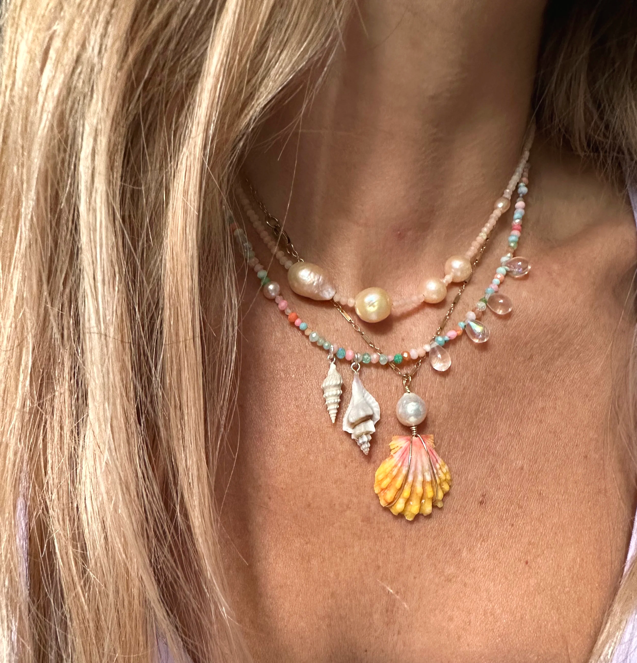 Stack of necklaces, chokers and pendants. Pink opals and freshwater pearls, rainbow opals with shell charms, and hawaiian sunrise shell pendant.