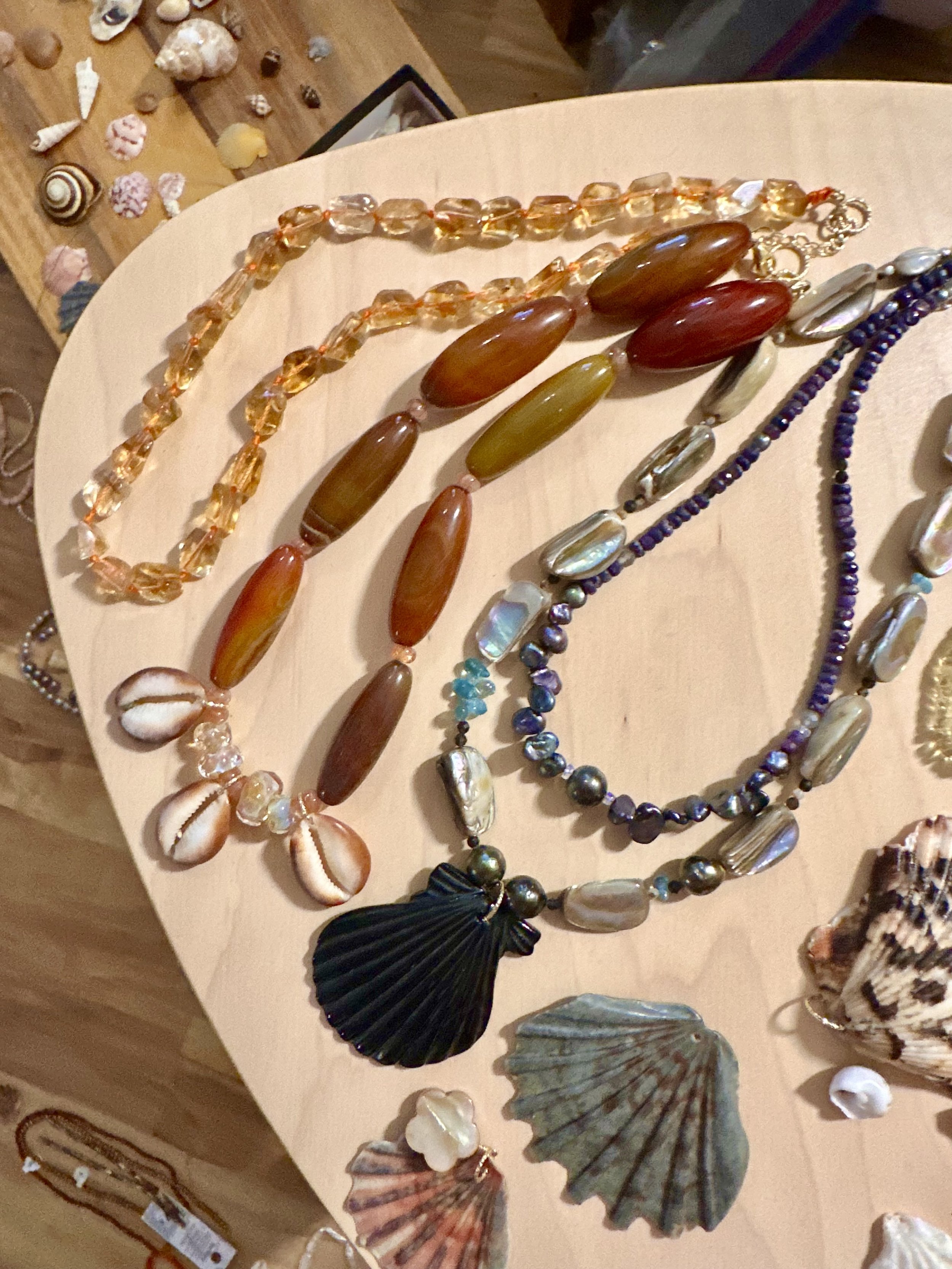 various one of a kind handmade shell, gemstone, and pearl necklaces.