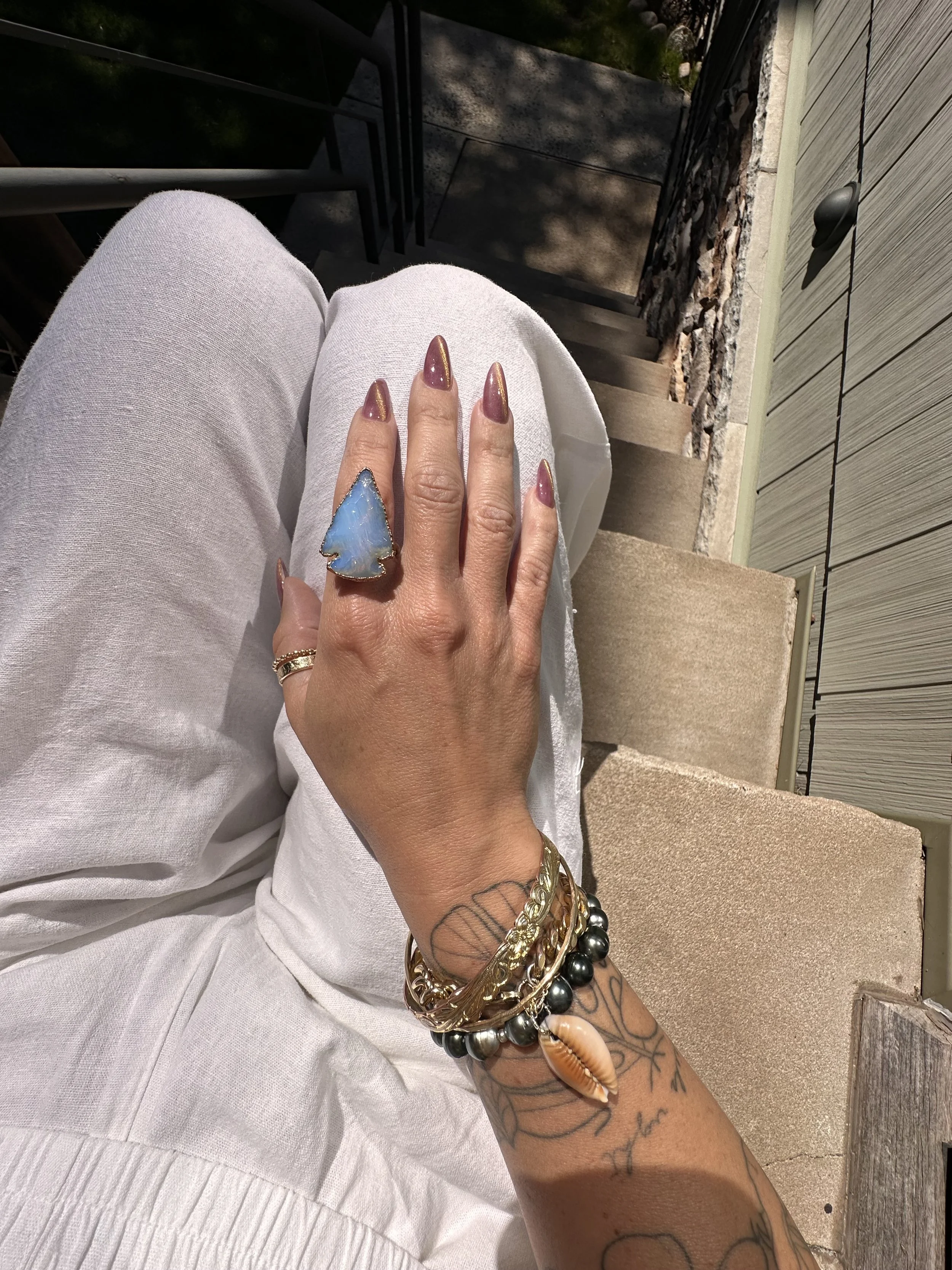 opal glass arrowhead copper ring with bracelet stack including tahitian pearl stretch bracelet and cowrie cuban link chain bracelet.