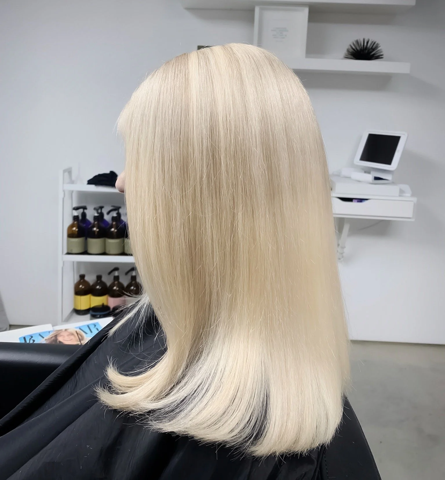 Blonde woman with shoulder-length hair sitting in a salon chair