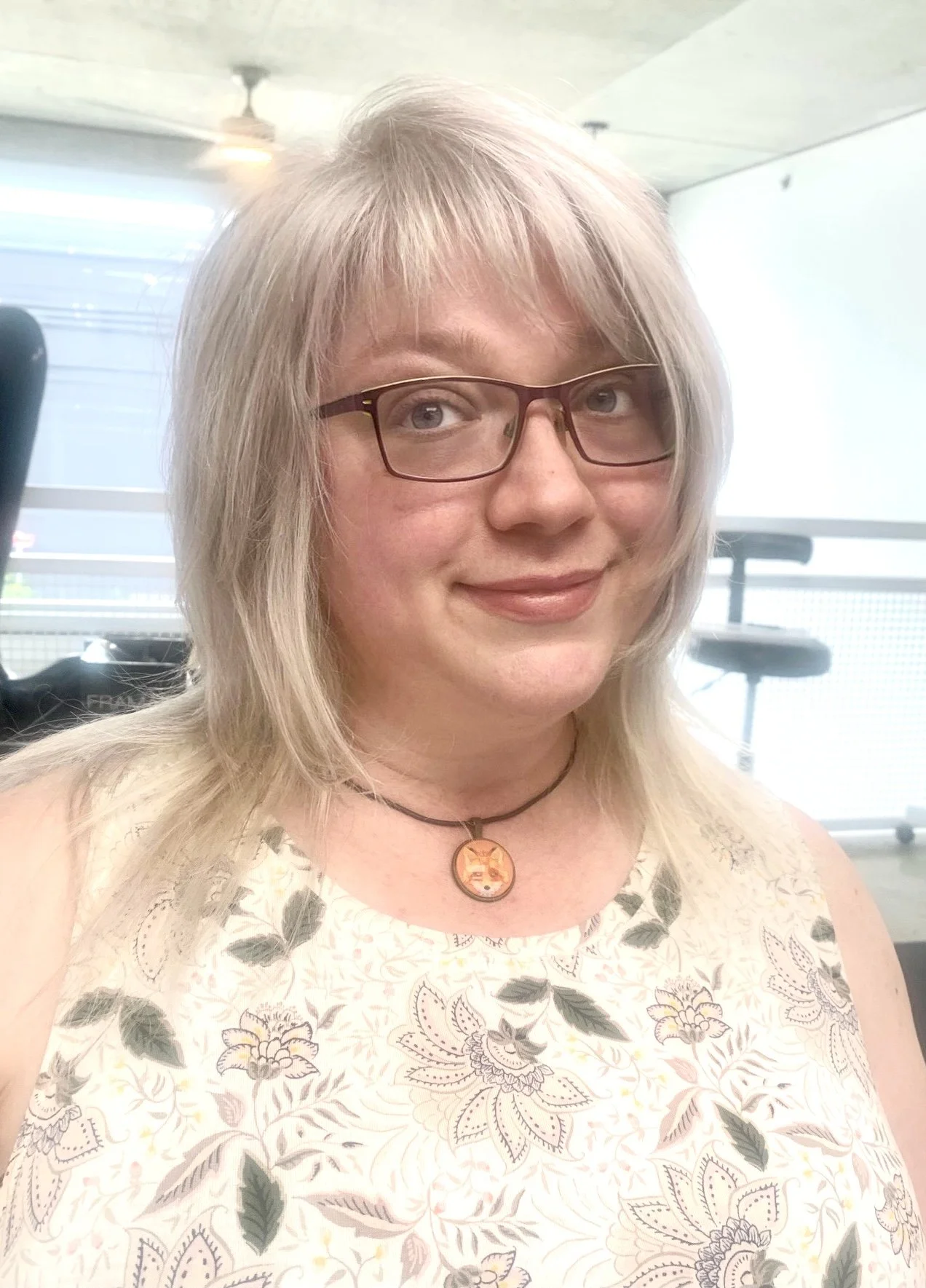 Person with light hair wearing glasses and a floral top.