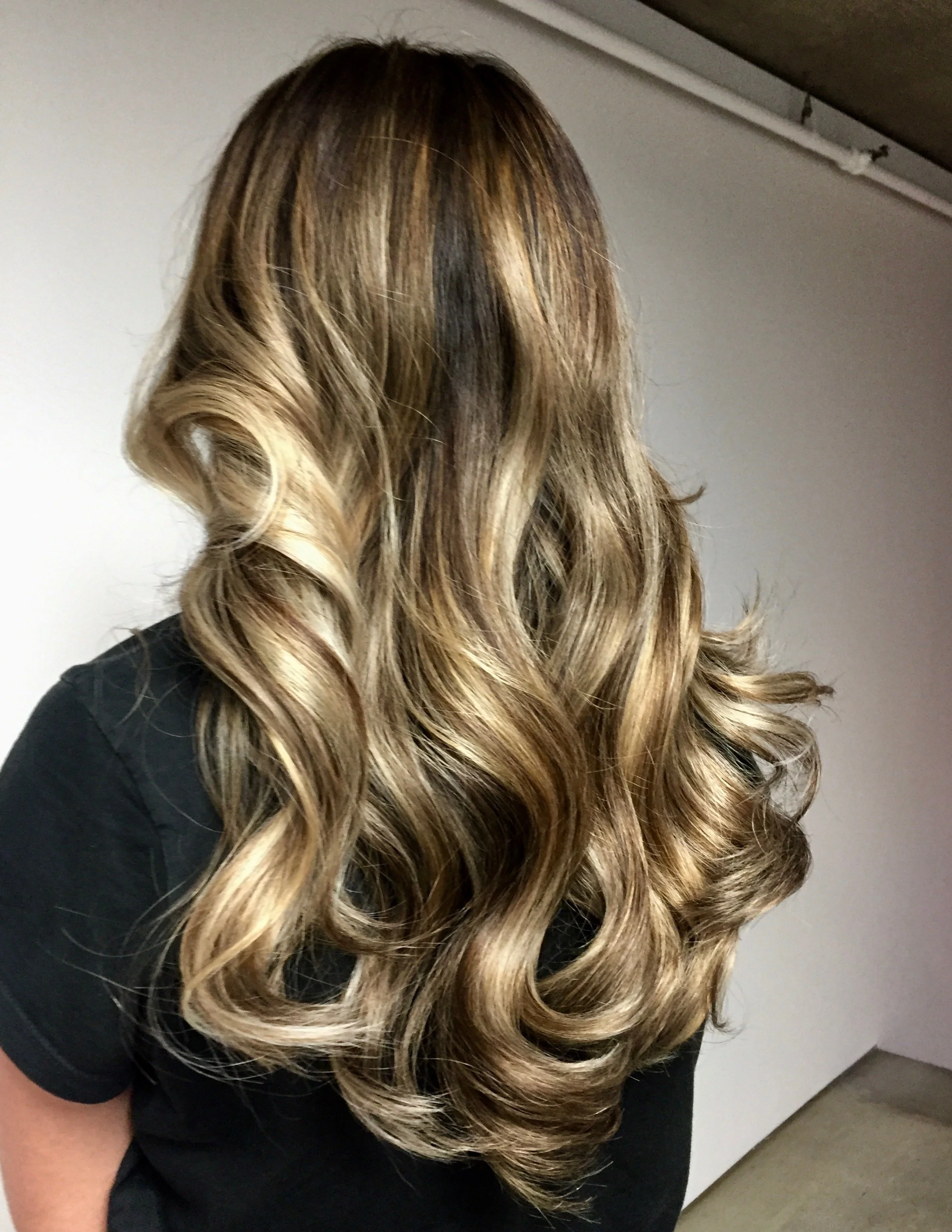 Back of a woman with long, blonde, wavy hair.
