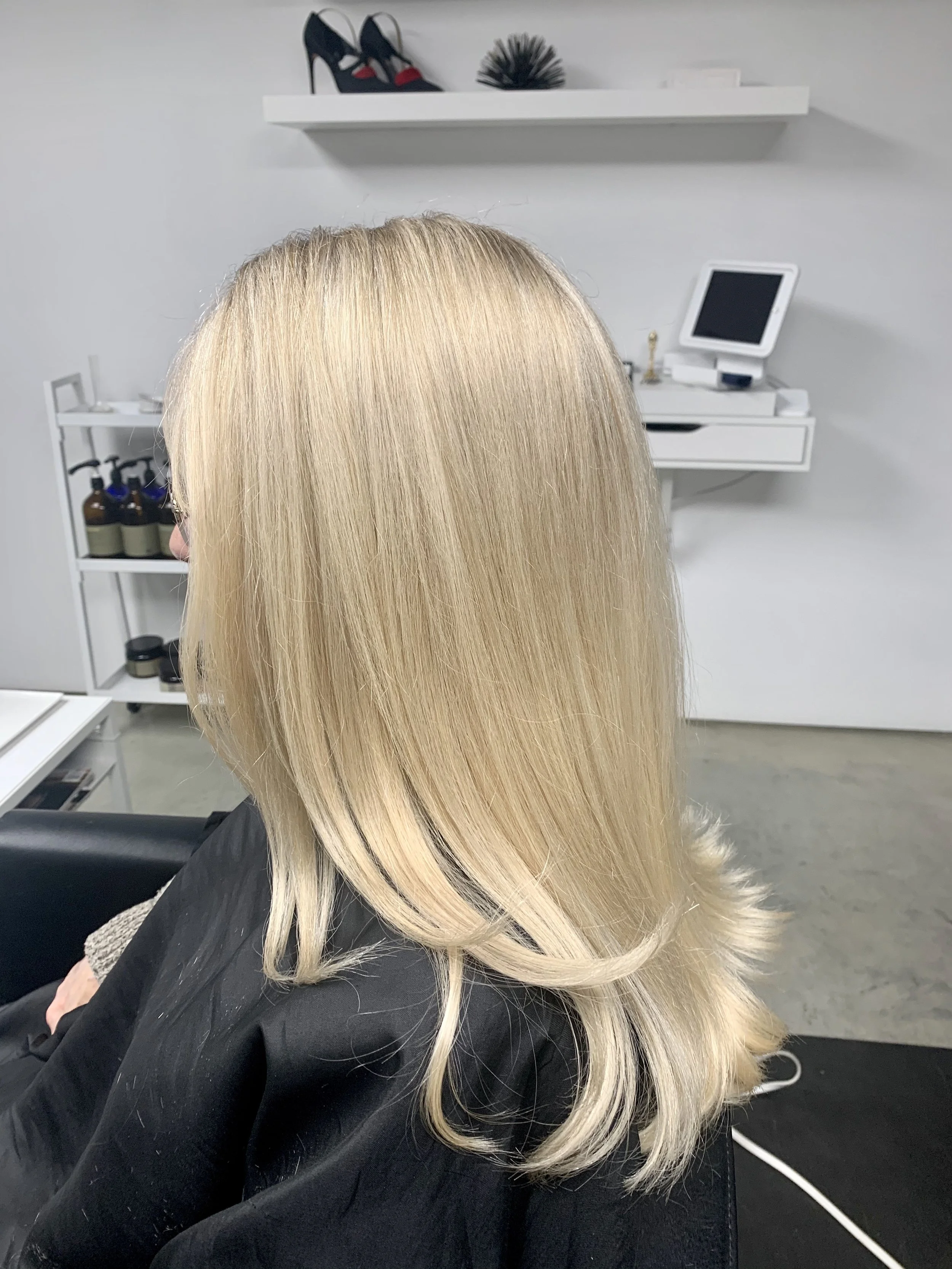 Blonde woman with styled hair sitting in a salon chair.