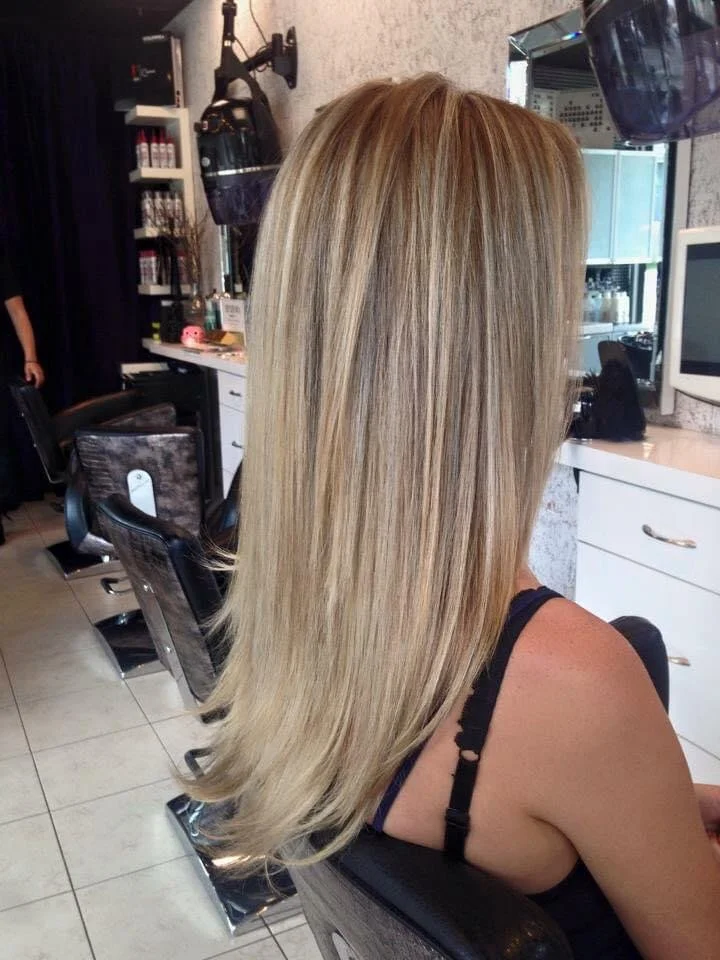 Woman with long, straight blonde hair sitting in a salon chair.