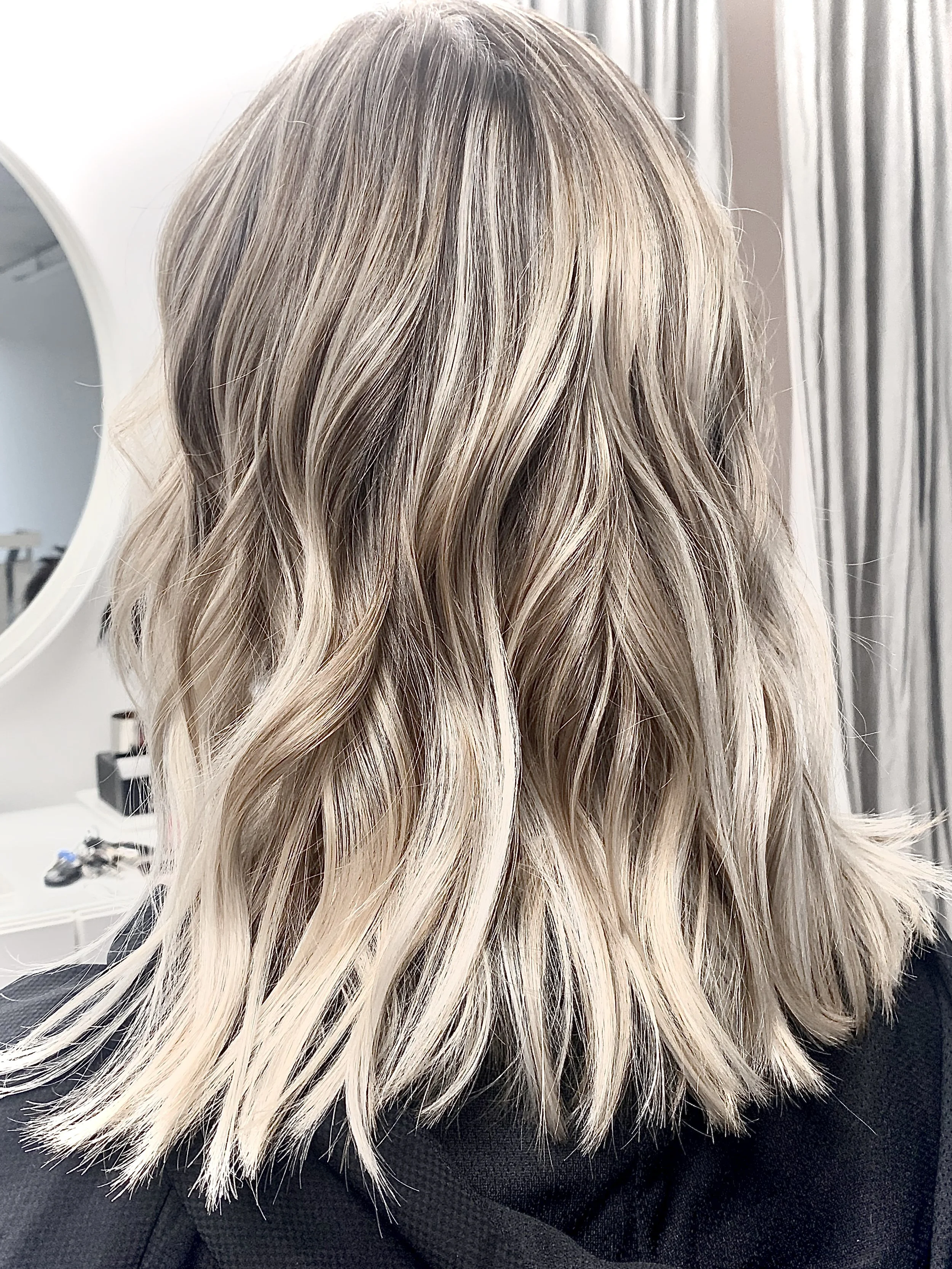 Shoulder-length blonde hair with waves in a salon setting.