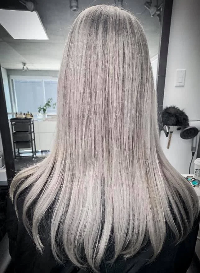 Back view of a person with straight, long blonde hair in a hair salon.