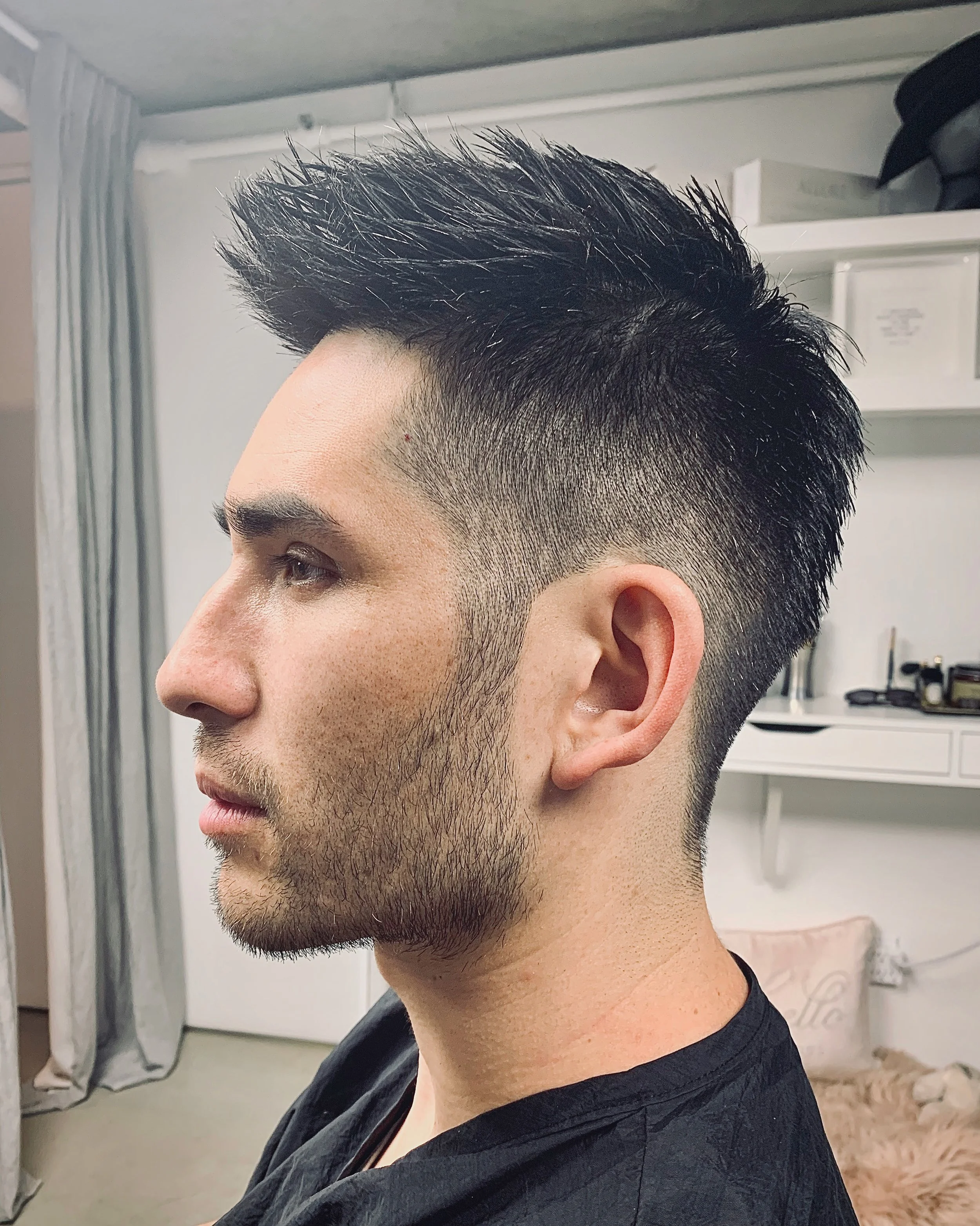 Side profile of a young man with a modern hairstyle featuring short, faded sides and longer, styled hair on top.