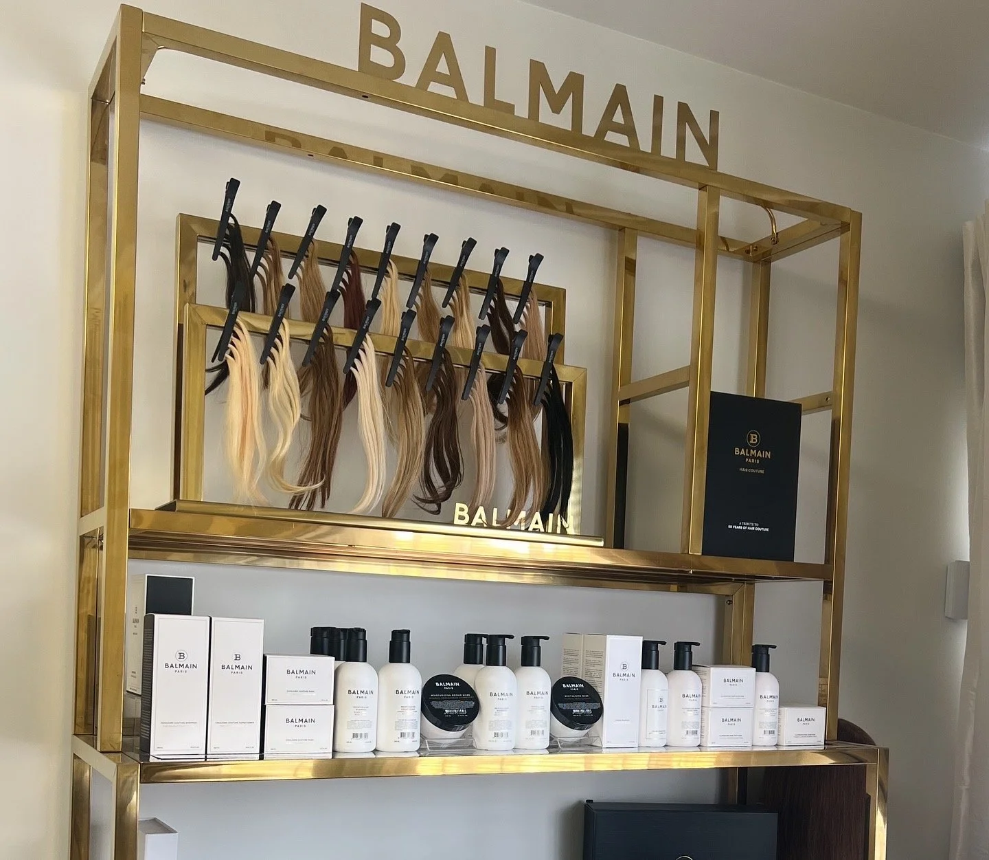 Display shelf with hair color samples, Balmain hair care products, and a Balmain Paris sign.