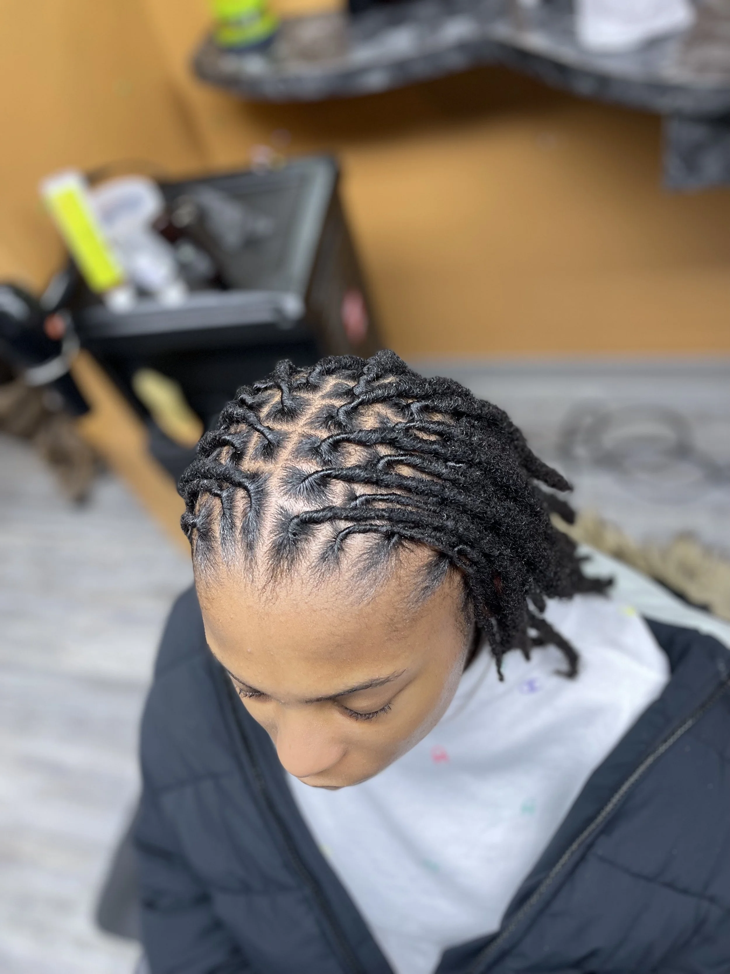 Top-down view of a woman with neatly styled dreadlocks, looking down.