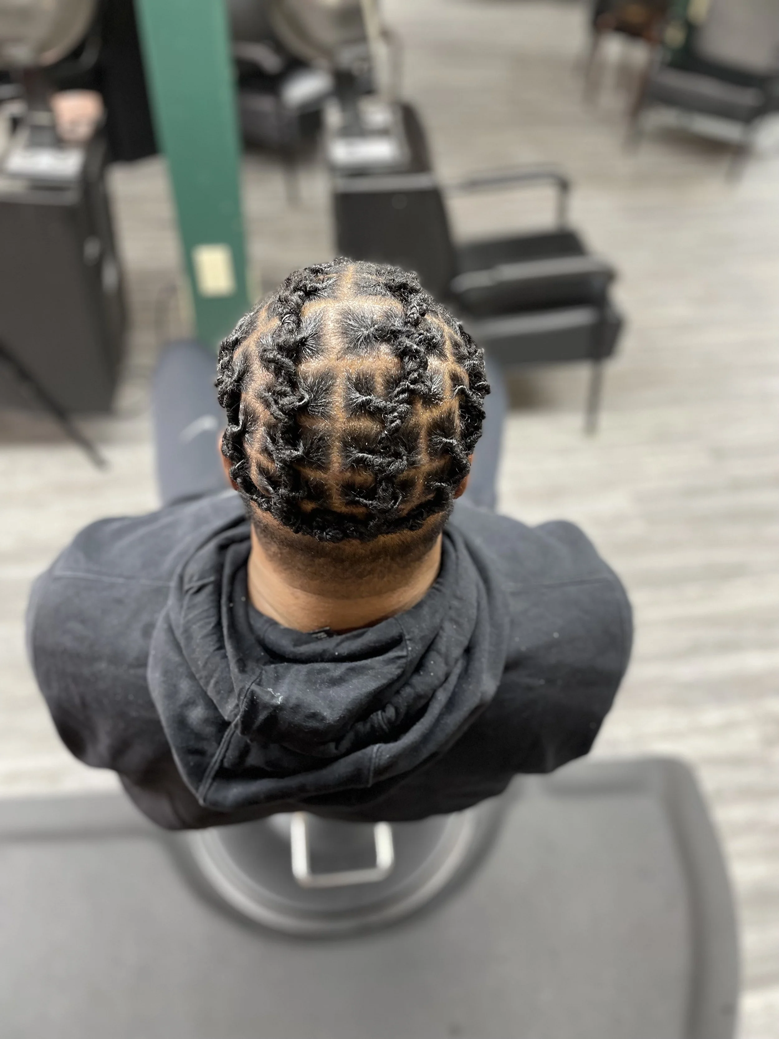 Top view of a person with neatly styled dreadlocks in a barber chair.