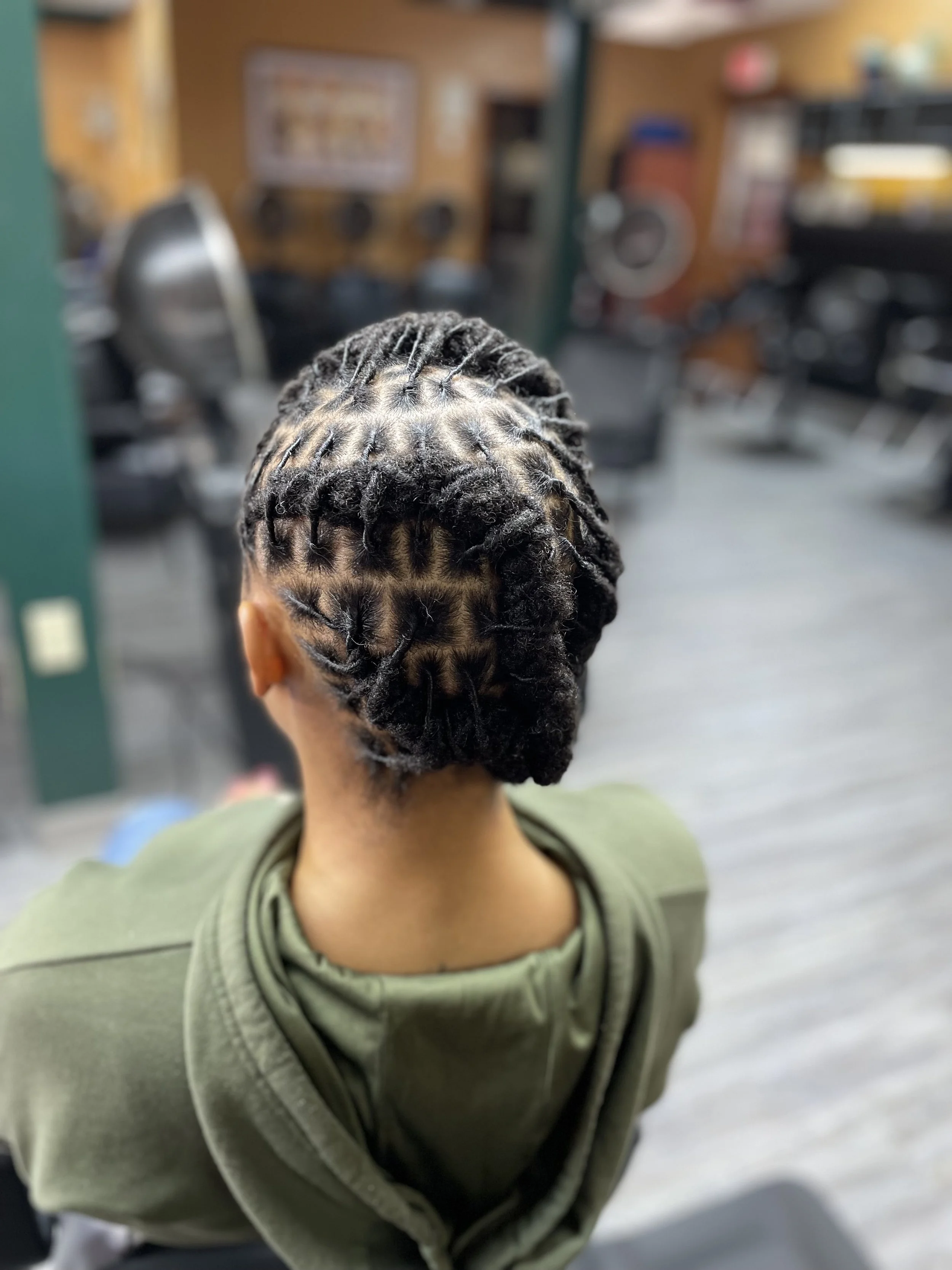 Young girl with freshly braided and cornrow hair, sitting in a barber shop or salon.