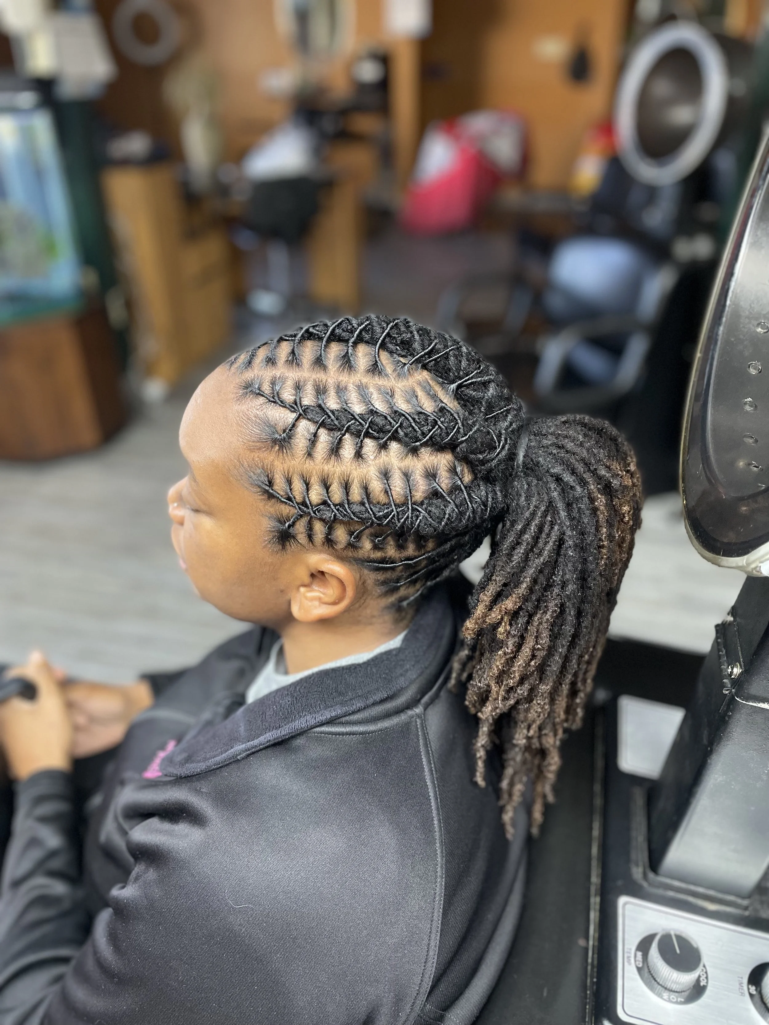 Woman with intricately styled fresh braids and dreadlocks in a salon