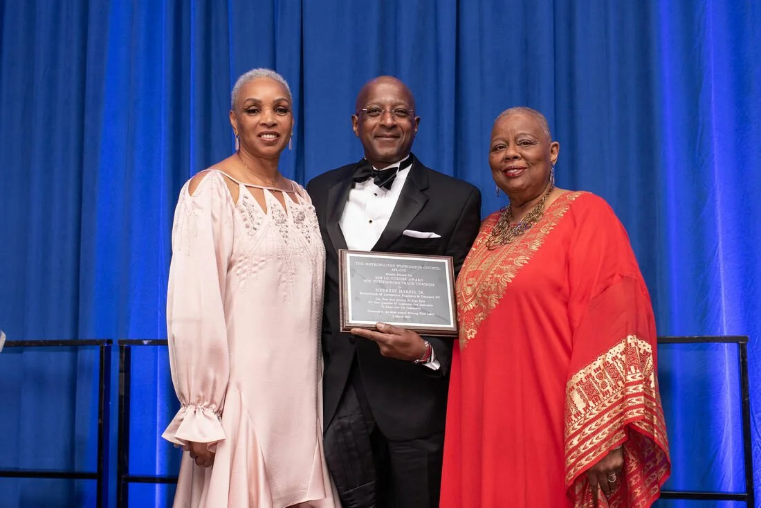 Three formally dressed African American men and womenEvening With Labor award winners pose with plaque