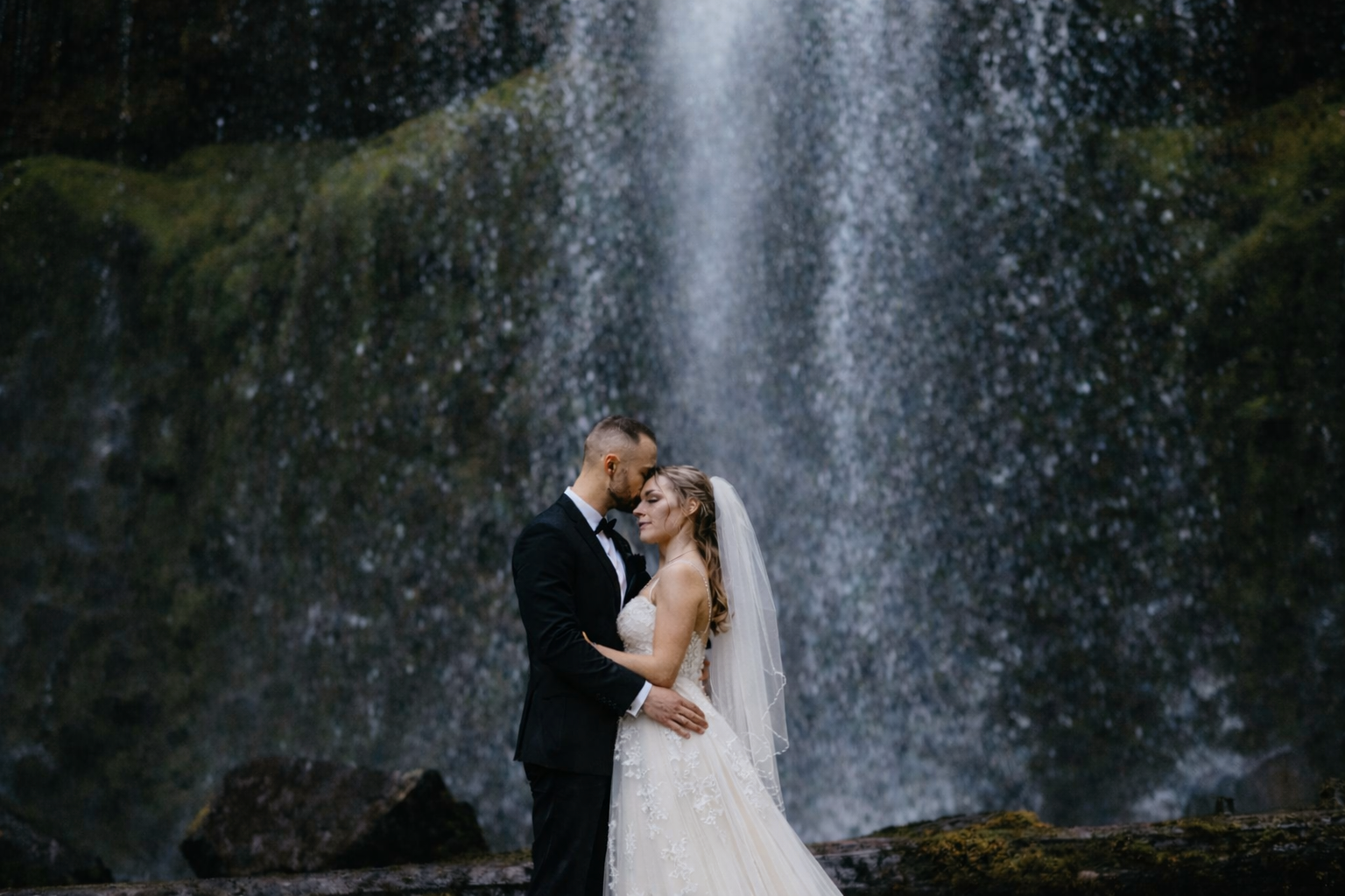 A couple embraces at a waterfall during their elopement in Oregon in the pew