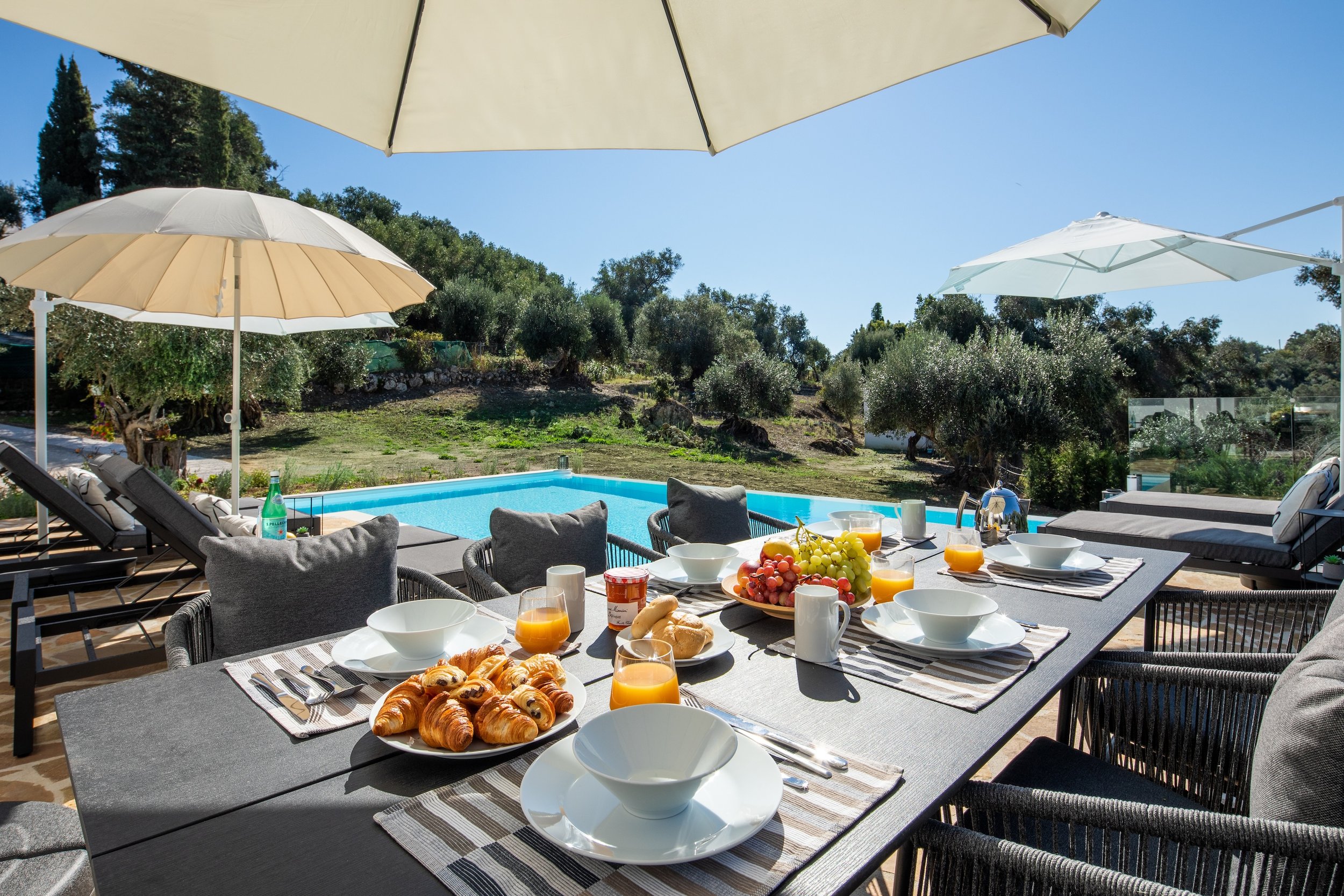 The patio dining table with breakfast on it, over looking the private swimming pool at Villa Icarus Corfu.