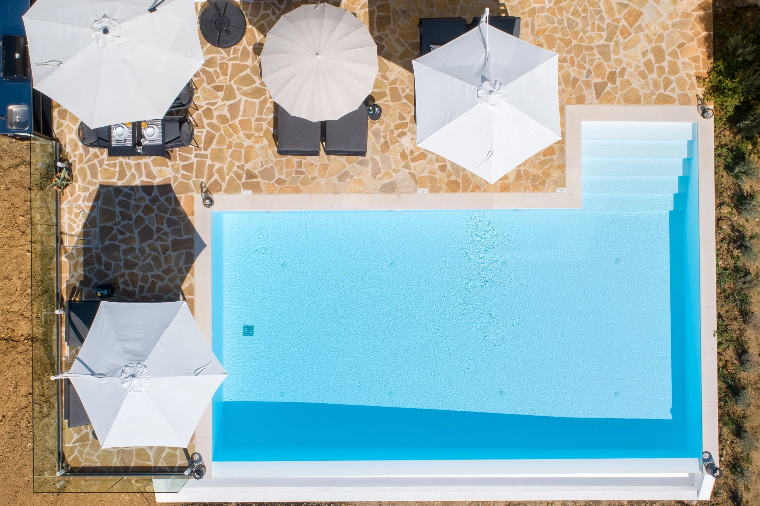 A top down shot of the patio and private swimming pool with open parasols at Villa Icarus Corfu.
