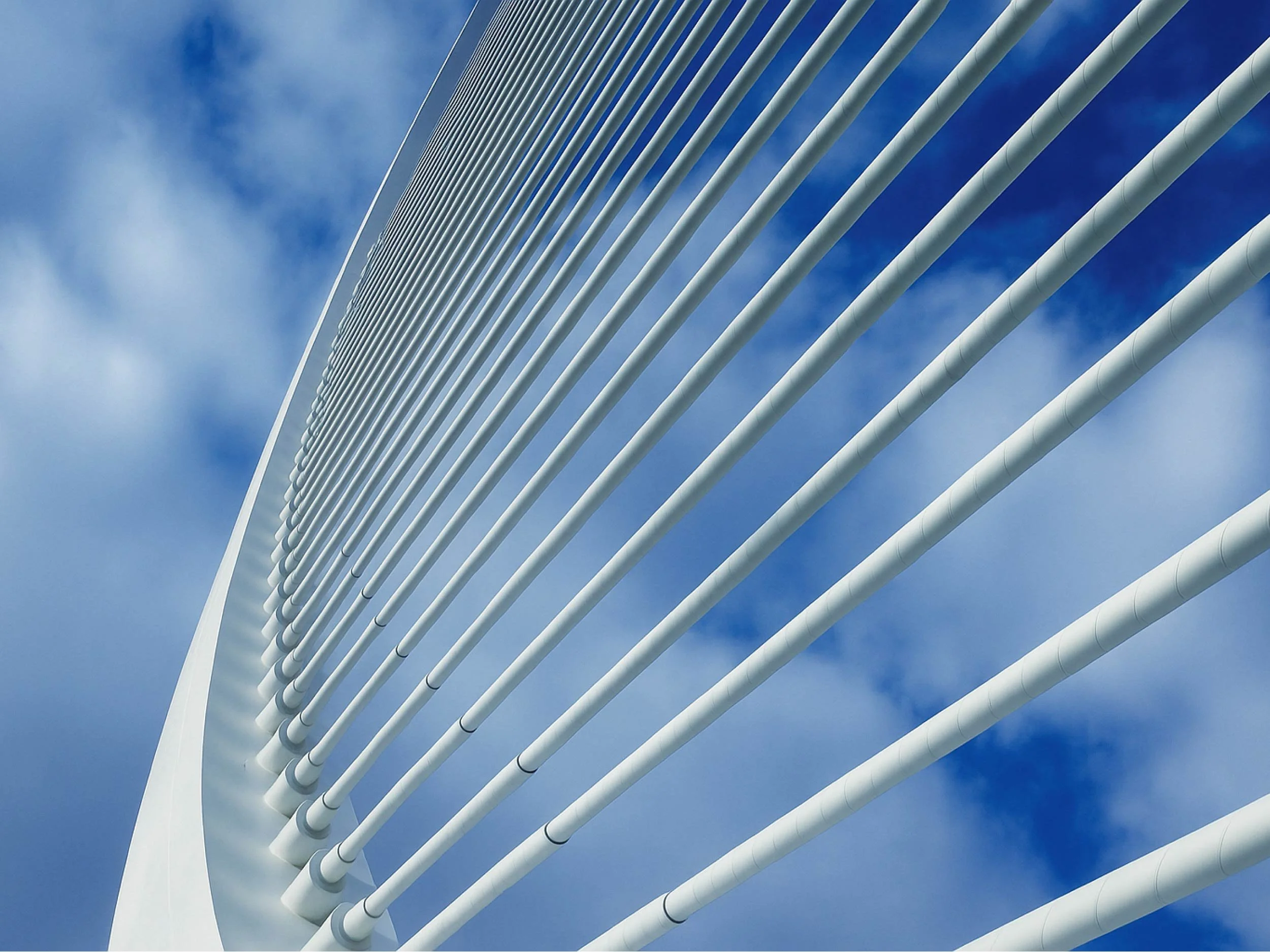 Close-up of a modern cable-stayed bridge with tall white towers and steel cables against a blue sky.