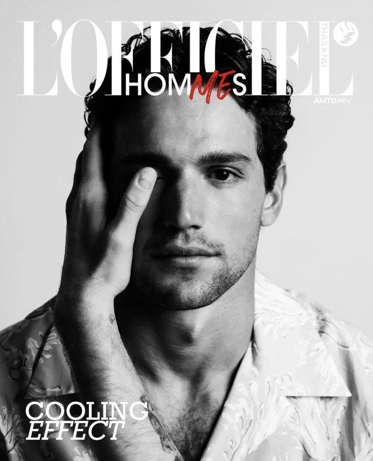 Black and white portrait of a man with dark, curly hair, gazing directly at the camera with his hand touching his face, on the cover of L'Officiel Hommes magazine with the text "COOLING EFFECT" at the bottom, and "L'OFFICIEL HOMMES" at the top.