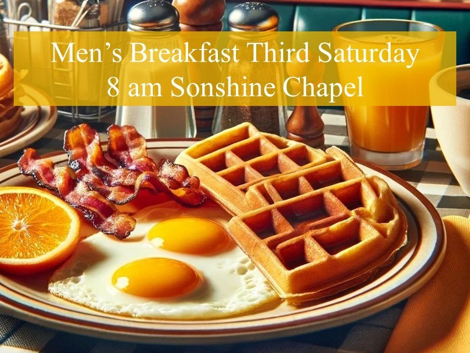 A plate of breakfast food including two sunny side up eggs, bacon, waffles, a half orange slice, and drinks on a table set for breakfast.