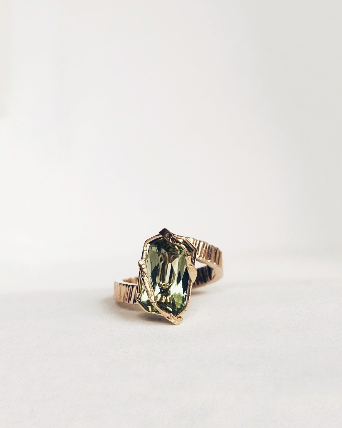 Unique gold ring with a large green gemstone on white background