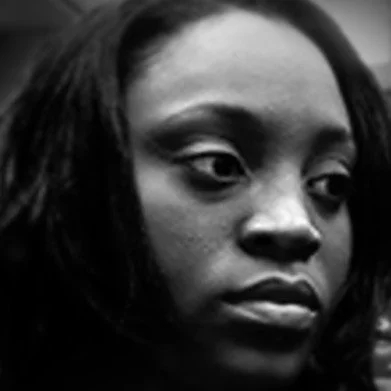 Close-up black-and-white portrait of a woman with shoulder-length hair, looking to the side.