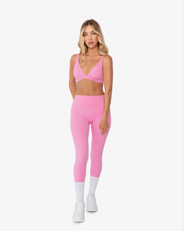 Woman wearing pink athletic outfit and white sneakers on white background