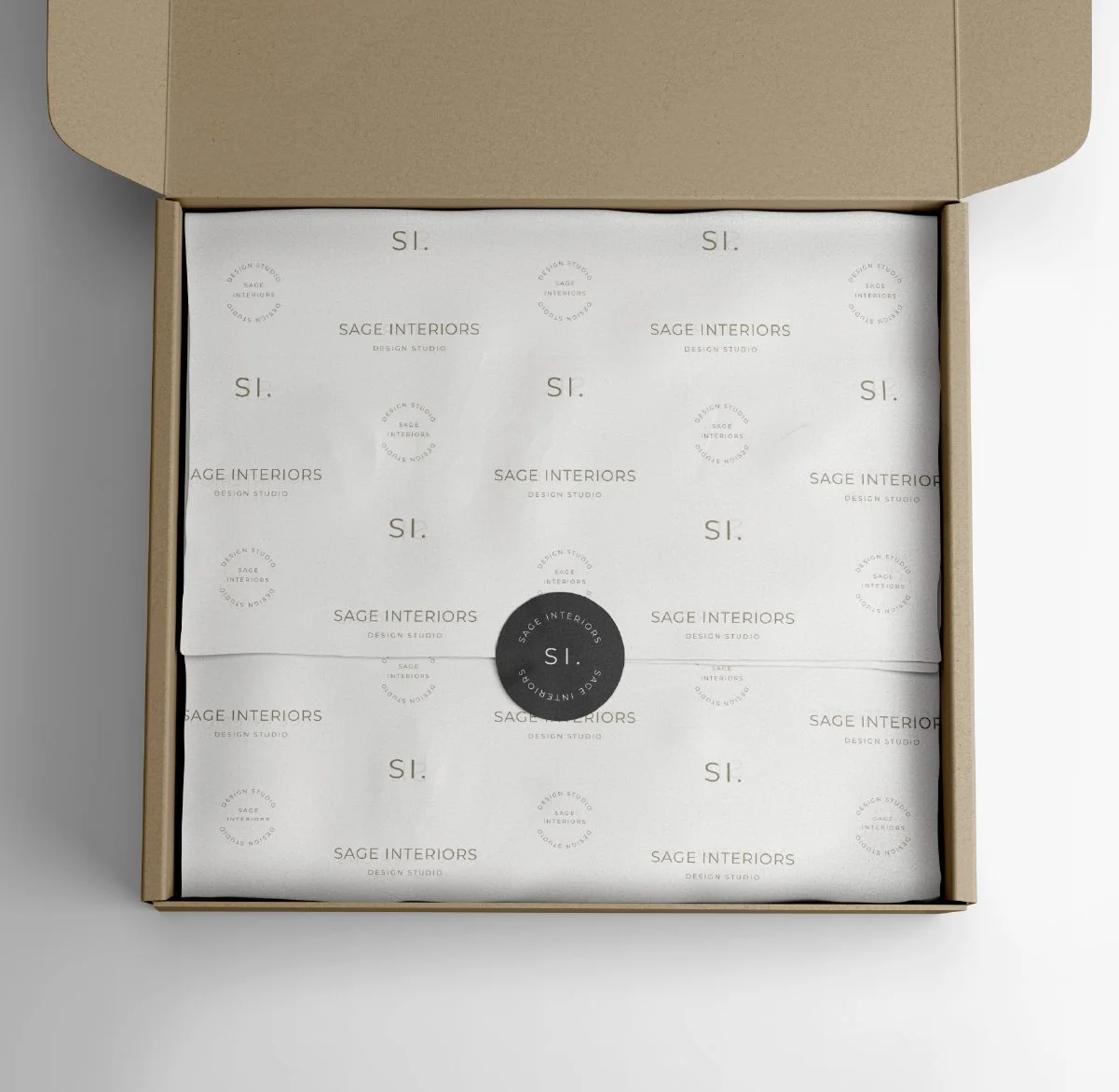 Open cardboard box containing branded tissue paper with 'Sage Interiors' logo and packaging sticker.