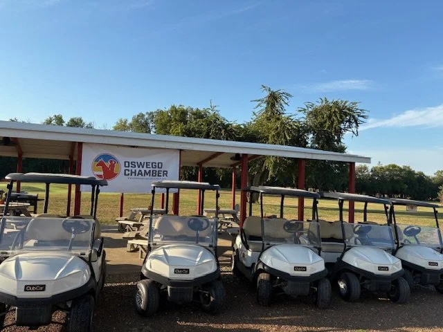 Golf carts at oswego golf course by pavillion with a Oswego chamber of commerce banner