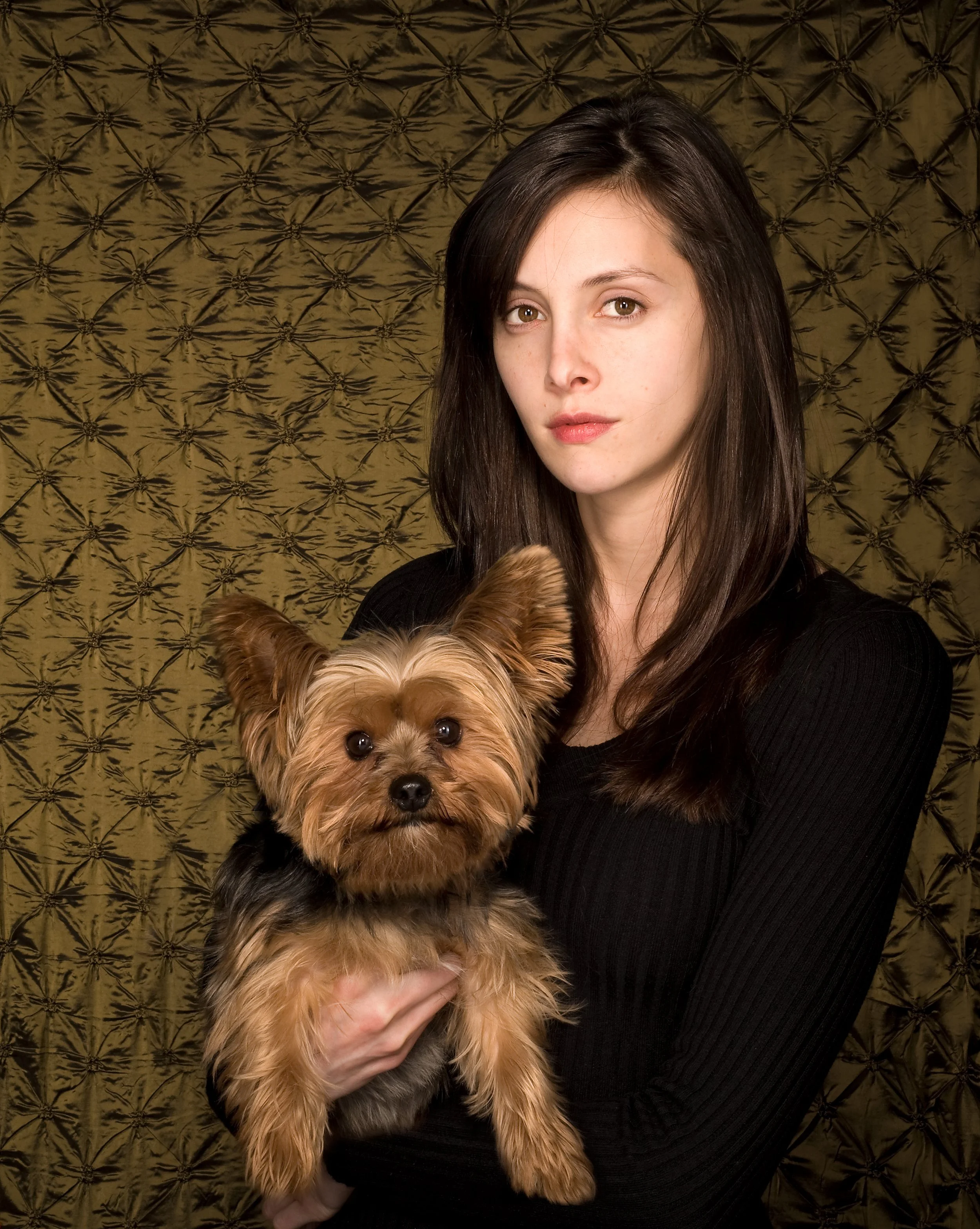 studio portrait of a woman in black holding her small dog
