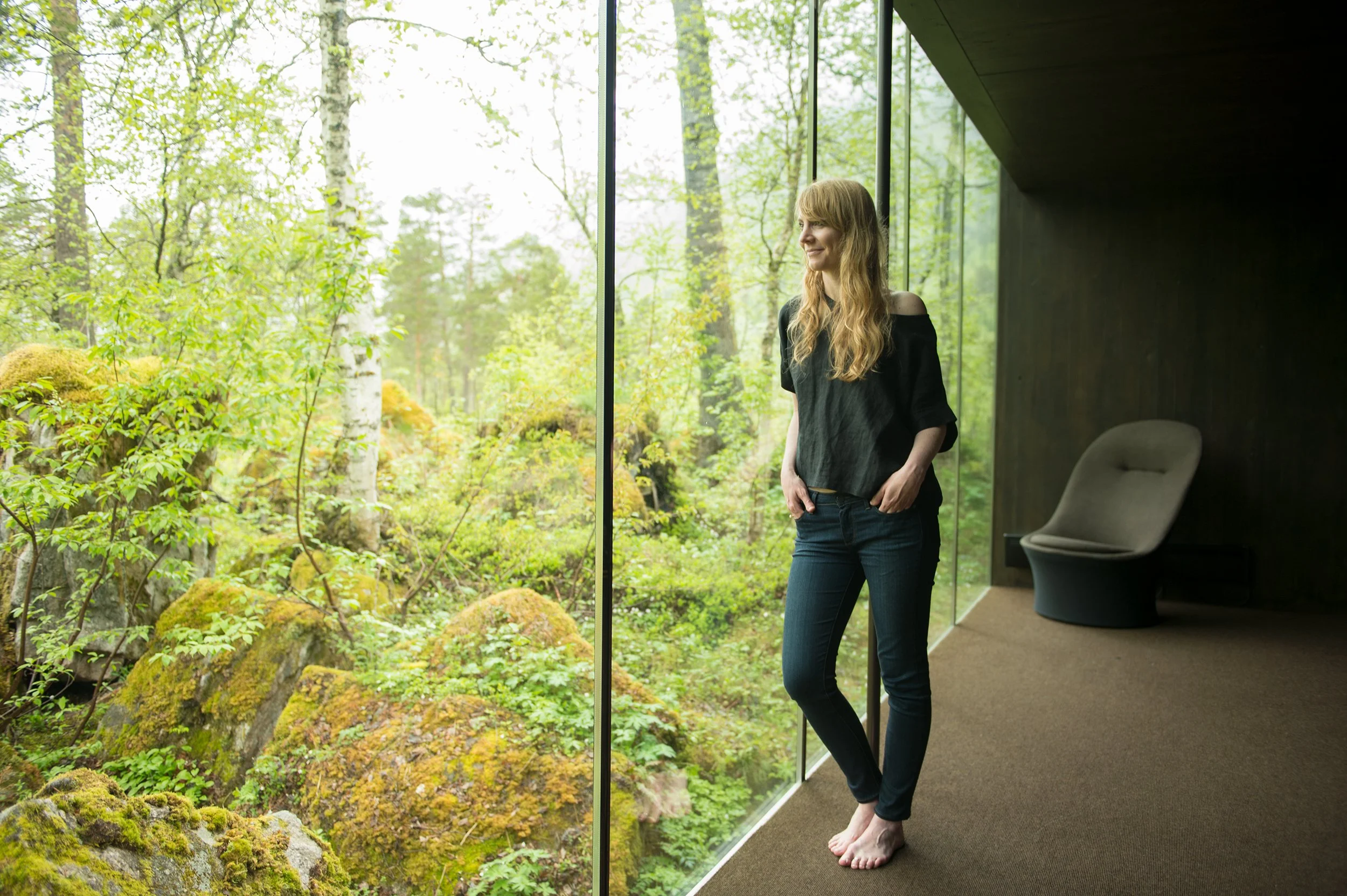 a woman looks out of a windwow at juvet landscape hotel in norway