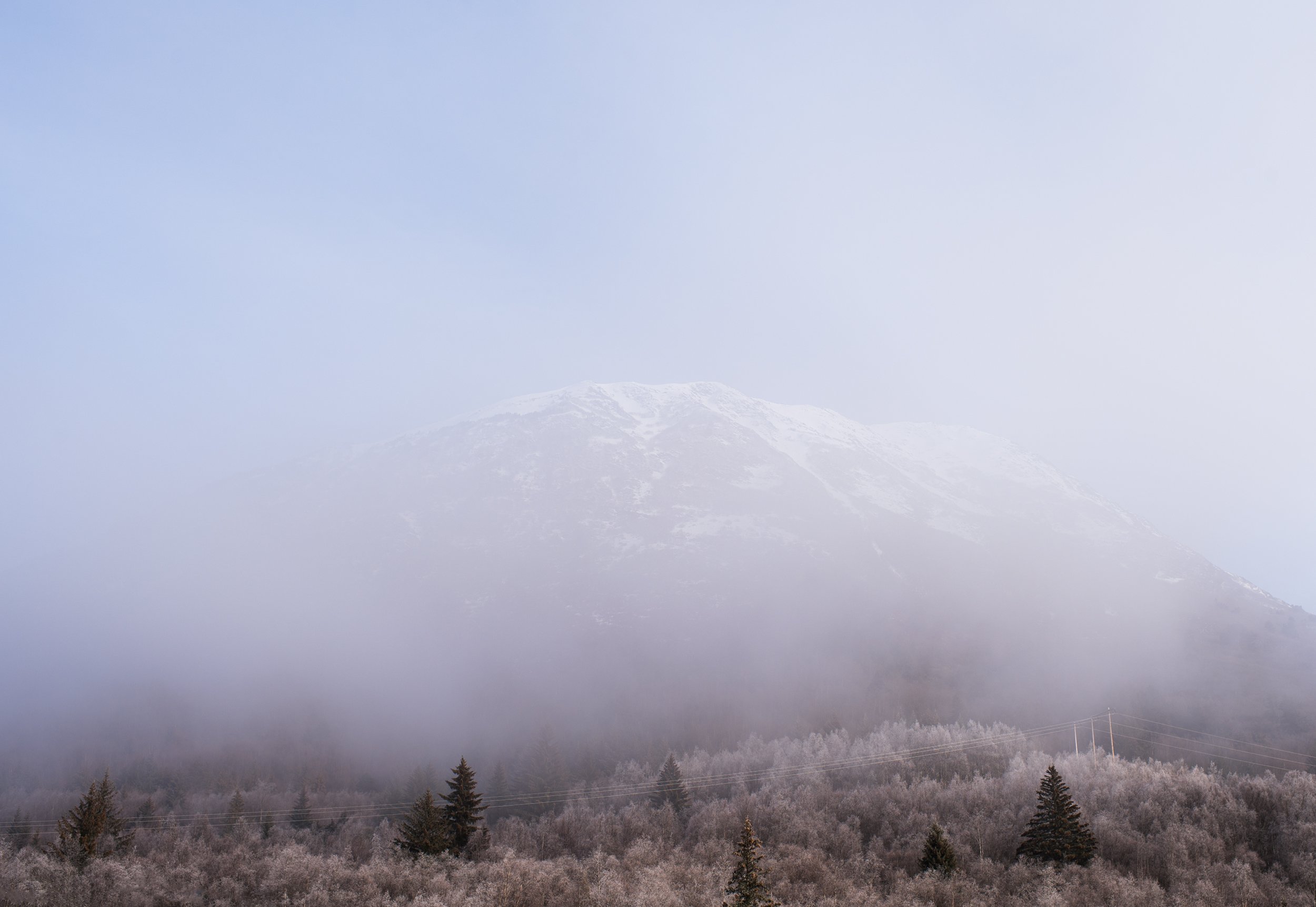 mountain in alaska barely visible through thick fog