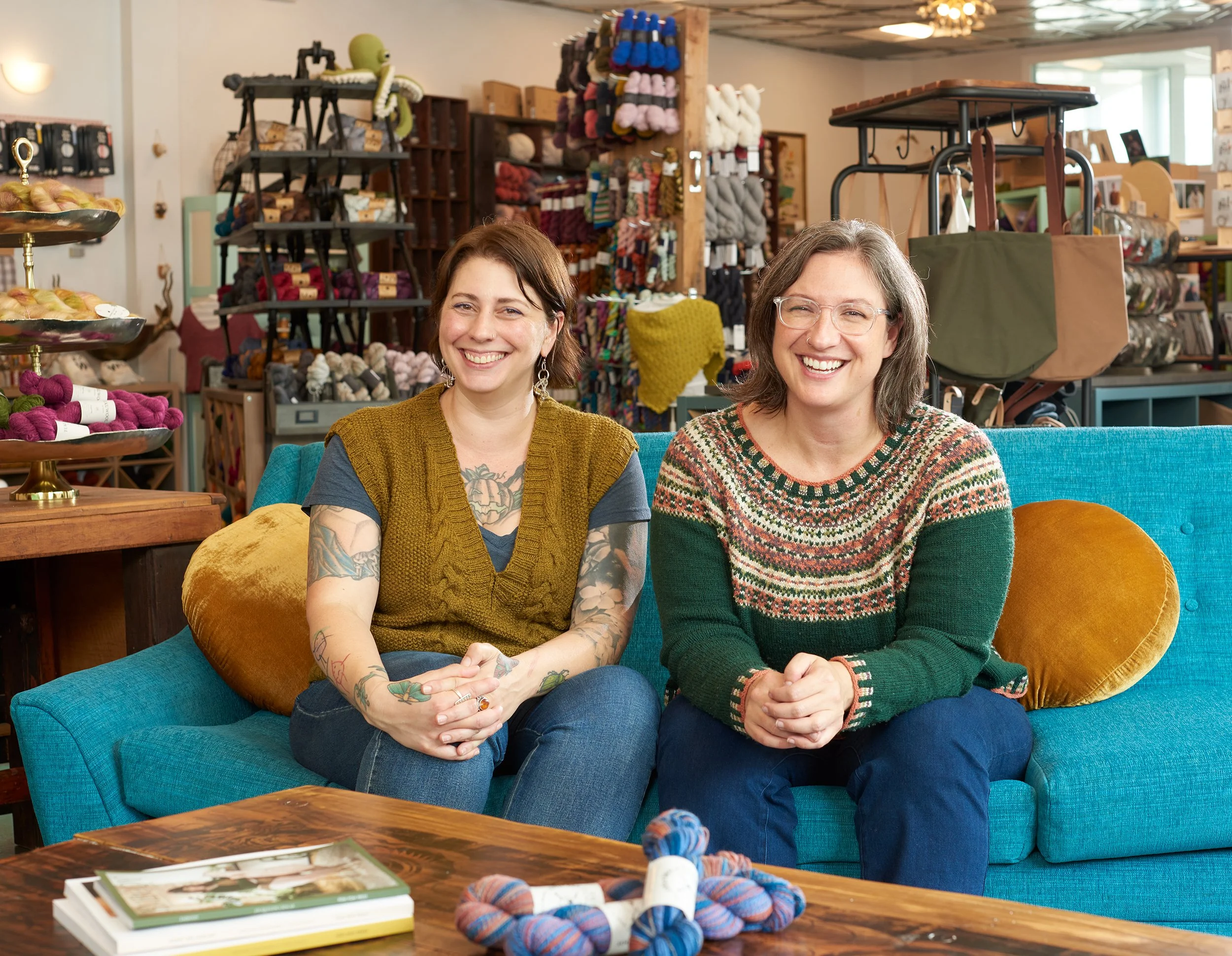 two female business owners posing for camera on blue couch