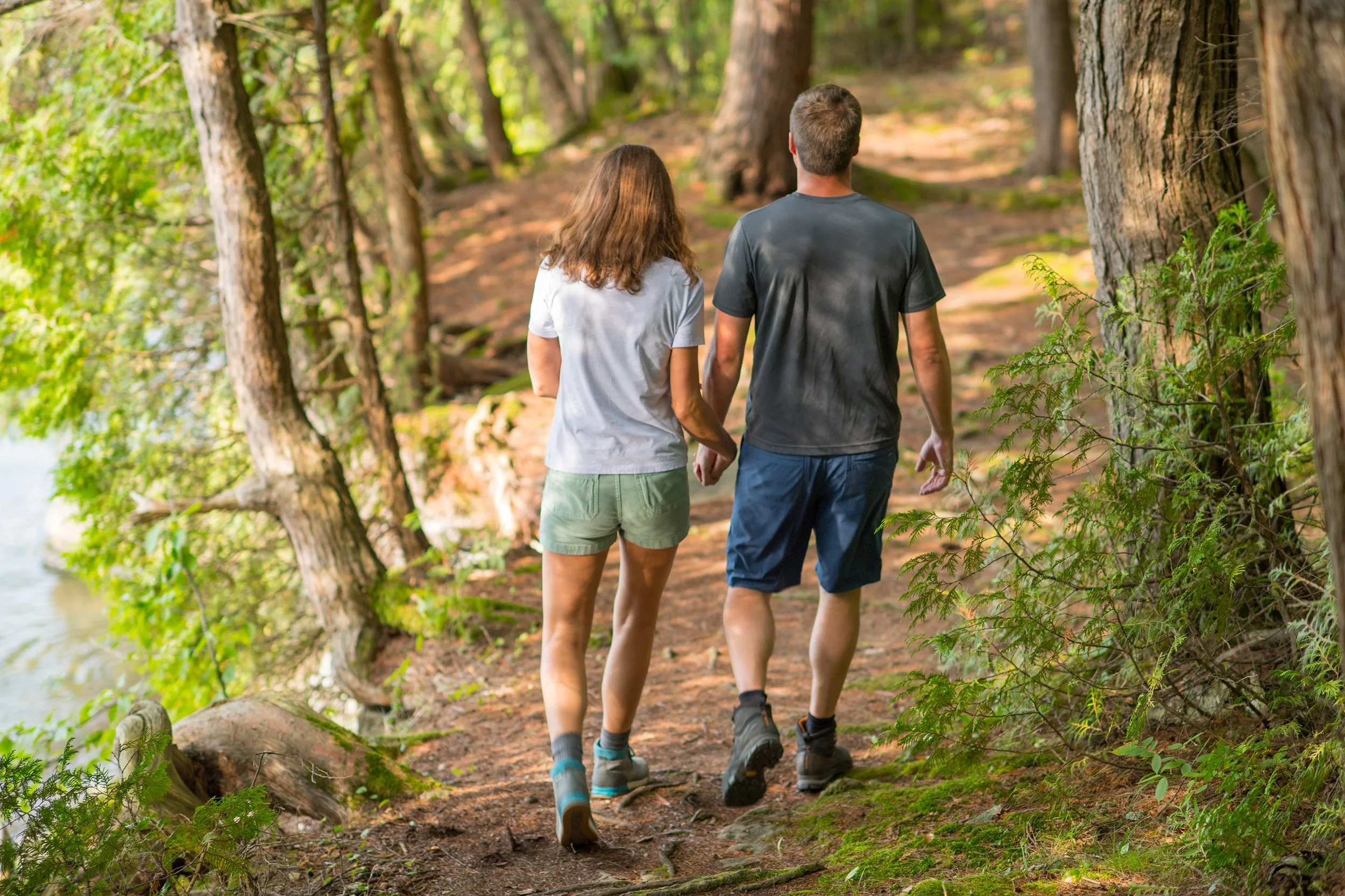 a male and female couple hold hands as they hike on a trail in Vermont