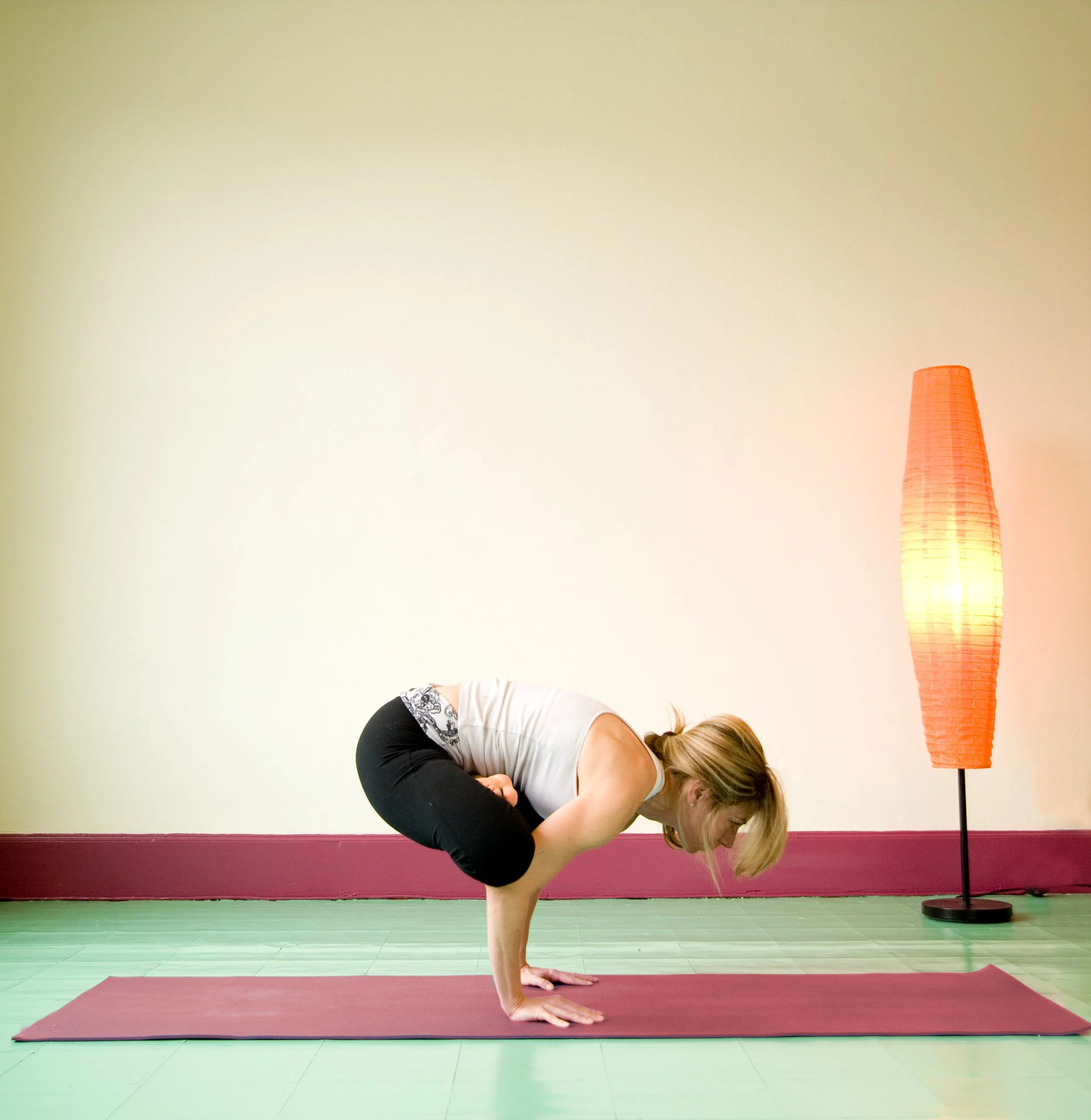 woman in yoga pose with orange lamp in background