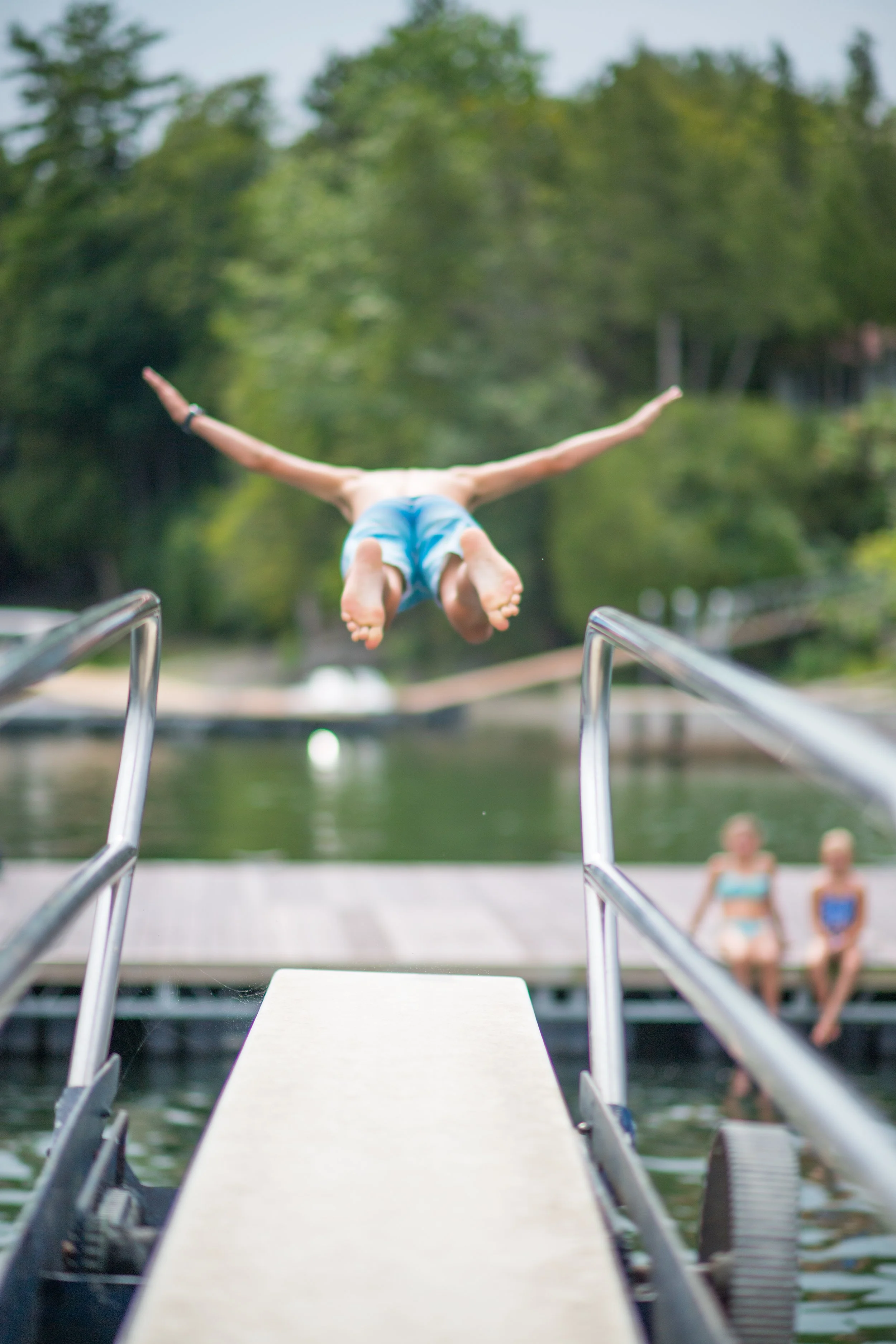 a boy dives of of diving board with arms spread