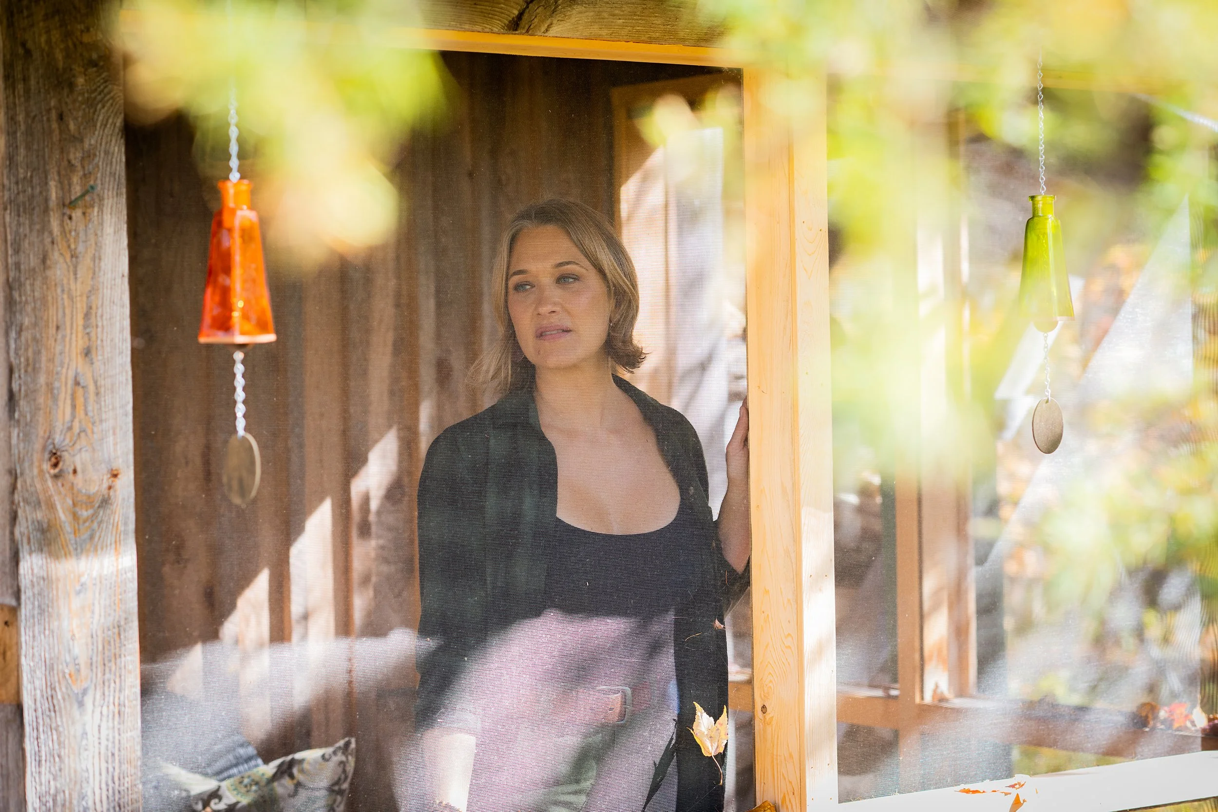 woman in green flannel shirt looks out of her screened in porch