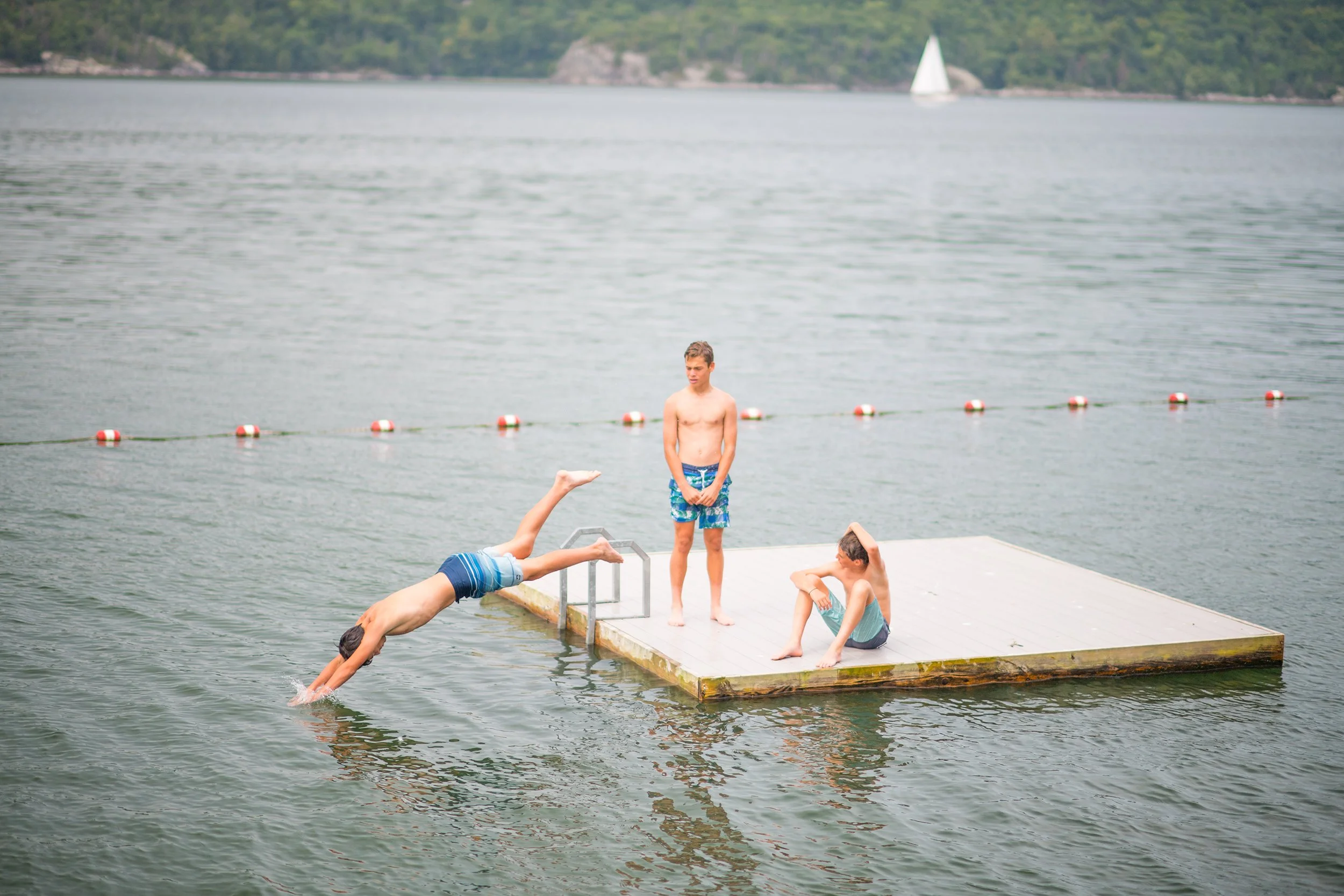 three boys on swimming platform on lake champlain at basin harbor