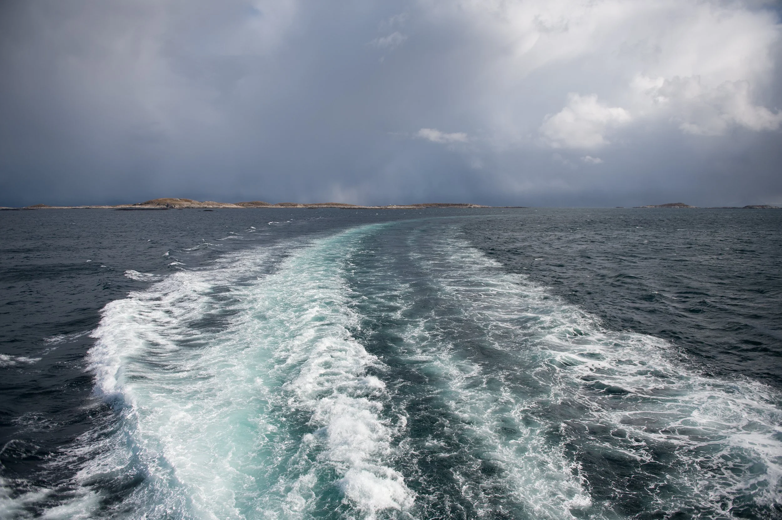 Ocean with waves behind a boat on a cloudy day