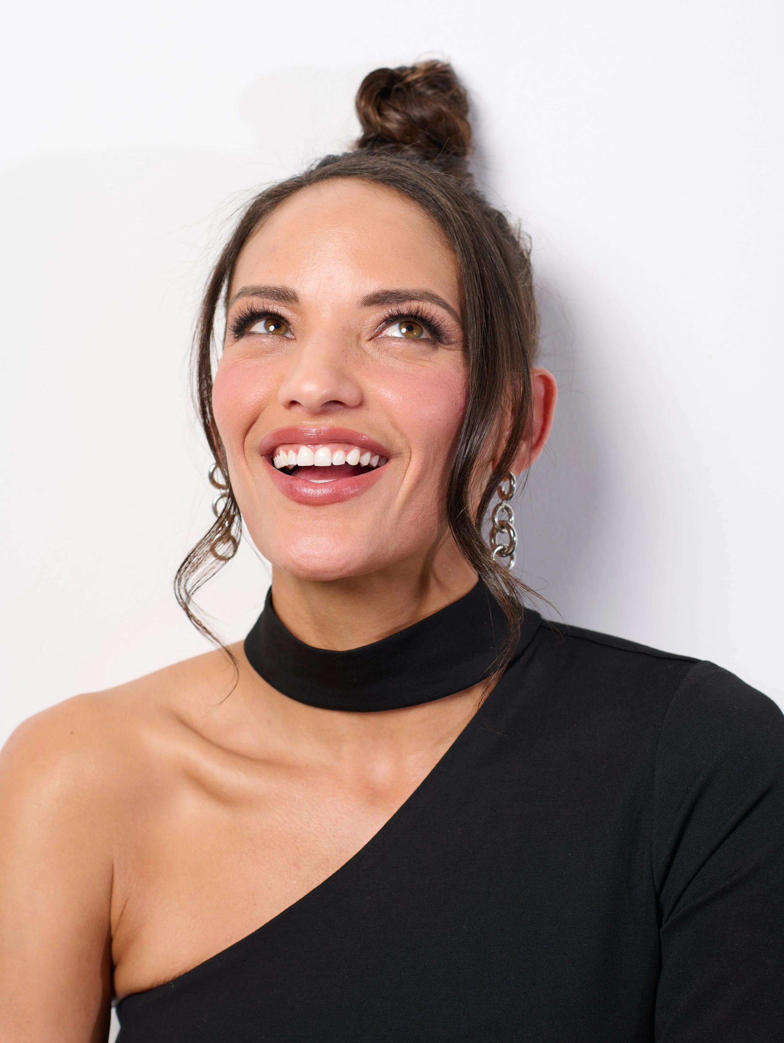 Burlington vermont fashion photographer michael heeney photographs a smiling woman in a black dress against a white studio wall 